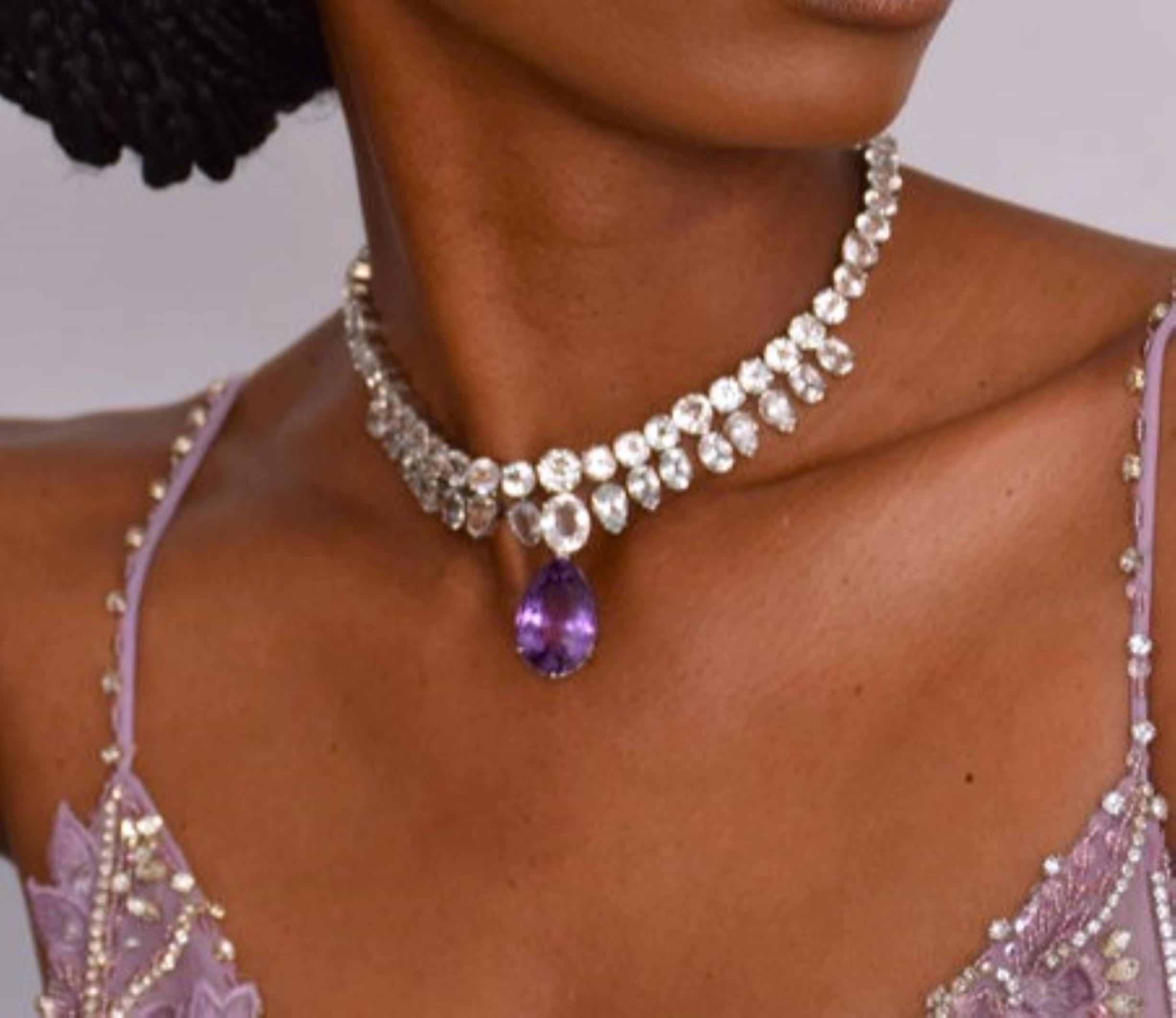 Elevate your jewelry collection with our exquisite Pear Cut Amethyst and Topaz Necklace. At the heart of this stunning necklace lies a captivating 10ct pear-cut amethyst gemstone, radiating with its enchanting purple hue. Surrounding the amethyst