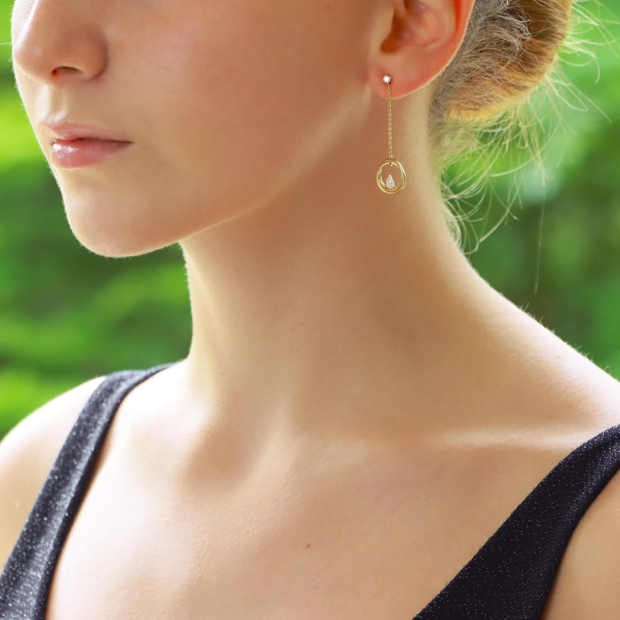Ein schönes Paar Diamant-Ohrringe in 18 Karat Gelbgold. 

Jeder Ohrring besteht zunächst aus einem einzelnen runden Diamanten mit Brillantschliff, der mit vier Krallen sicher gefasst ist. An diesem Ohrstecker hängt eine feine Kette, an der zwei