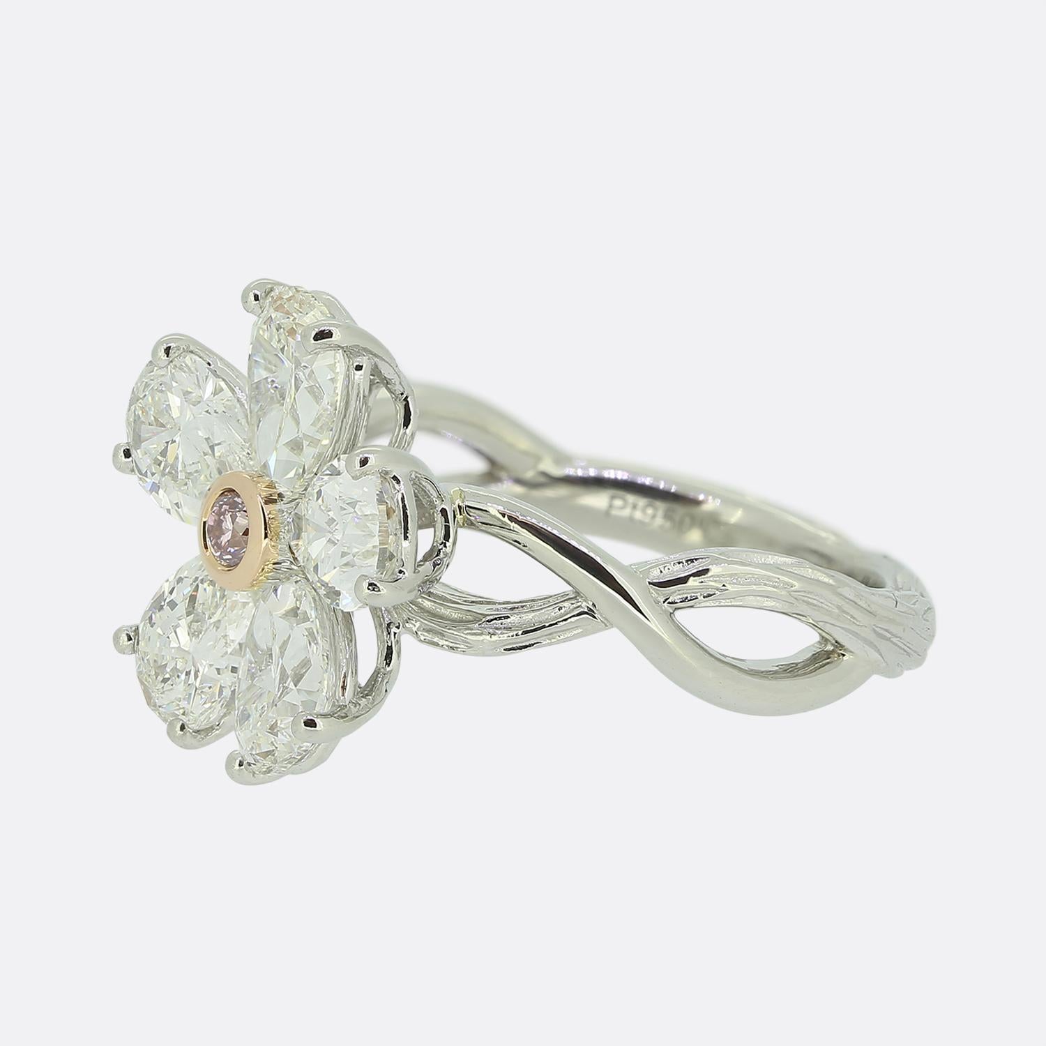 Here we have a truly stunning diamond flower ring. The ring is crafted in platinum and features five bright white pear cut diamonds with a fancy pink coloured diamond in the centre. It has an elegant textured twisted band adding to the flora design.