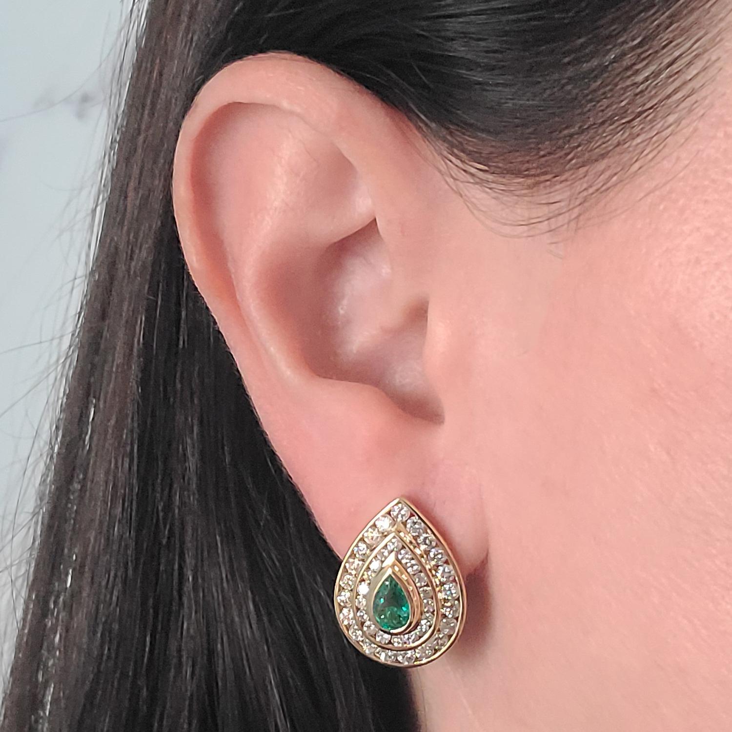 18 Karat Yellow Gold Pear Shaped Earrings Featuring 2 Bezel Set Emeralds Totaling Approximately 1.00 Carat Surrounded By 78 Channel Set Round Brilliant Cut Diamonds of SI Clarity and H Color Totaling An Additional 3.00 Carats. Pierced Post with