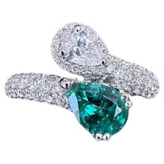 Anillo cruzado de esmeralda pera y diamante pera en oro blanco de 18k