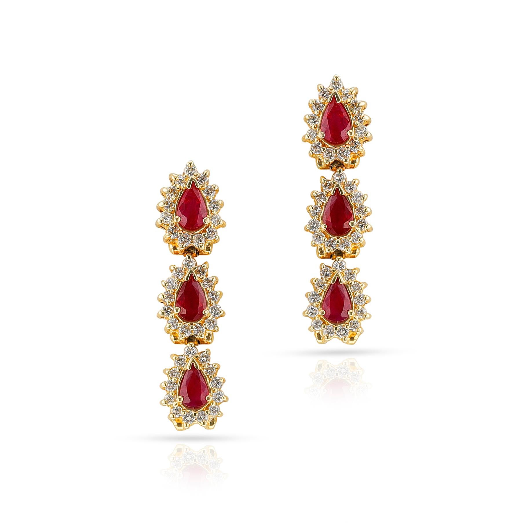 A pair of Three Pear Shape Rubies surrounded by diamonds in dangling earrings, made in 14k Yellow Gold. The total weight of the earring is 9.44 grams. The total weight of the rubies is 2,20 carats and the total weight of the diamonds is appx. 1.50