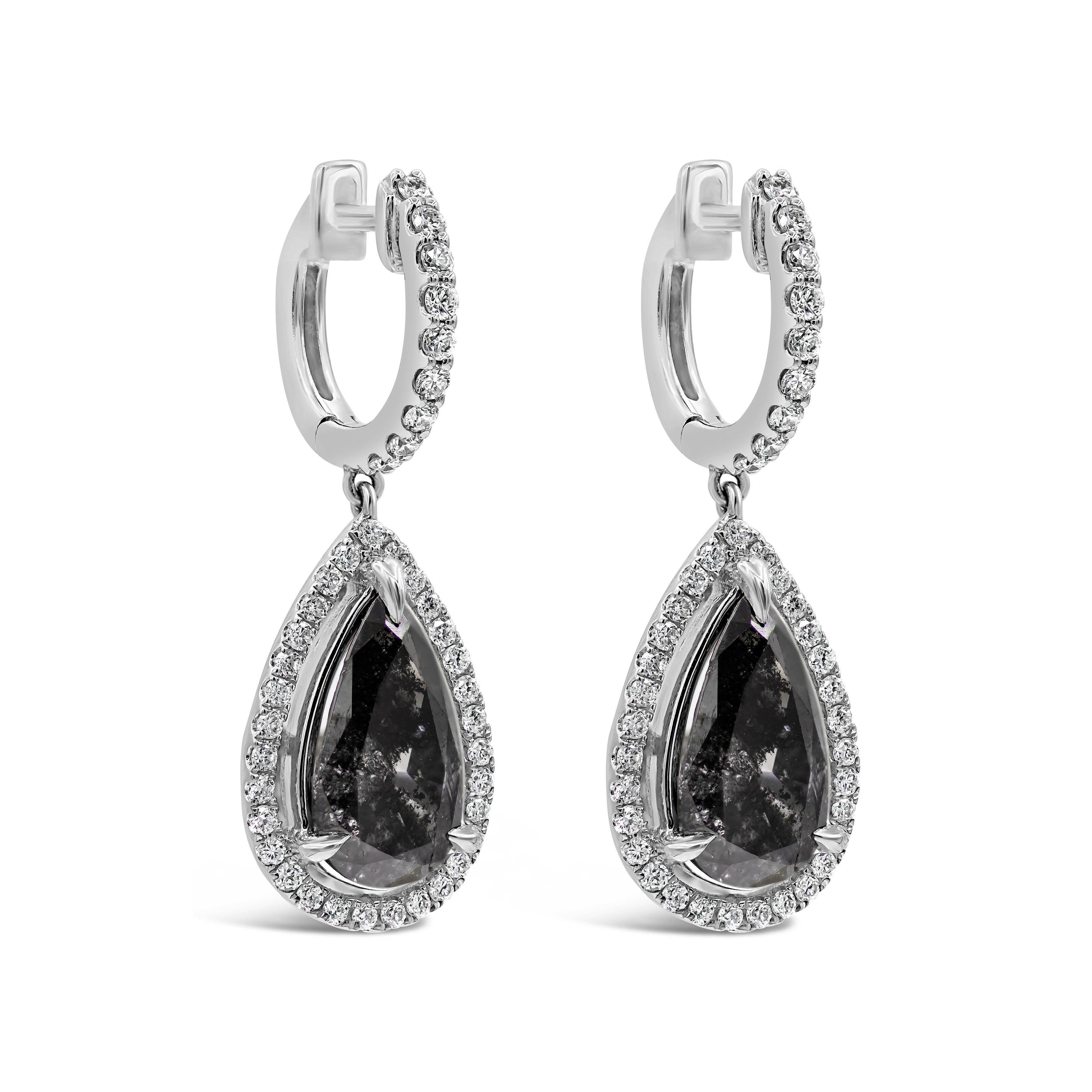 A beautiful pair of drop earrings showcasing 2 pear shape black diamonds weighing 3.17 carats total, surrounded by a single row of round brilliant diamonds weighing 0.52 carats total. Each earring is suspended on a diamond encrusted hoop and made in