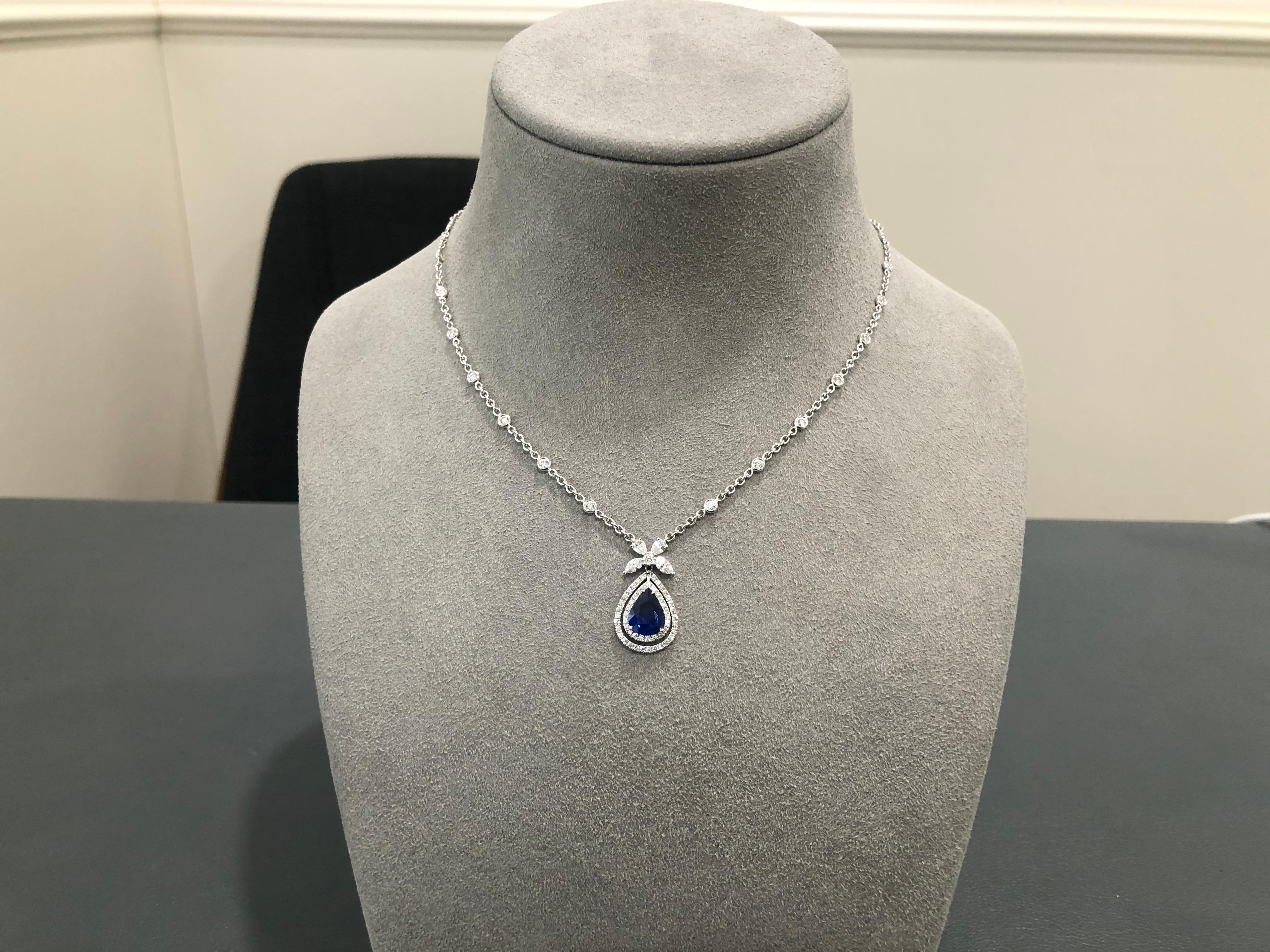 Features a 1.88 carat pear shape blue sapphire center accented by two rows of round brilliant diamonds. Suspended on a  pear and marquise cut diamond surmount attached to a diamonds by the yard chain in 18k white gold. Weight of the diamonds 1.44