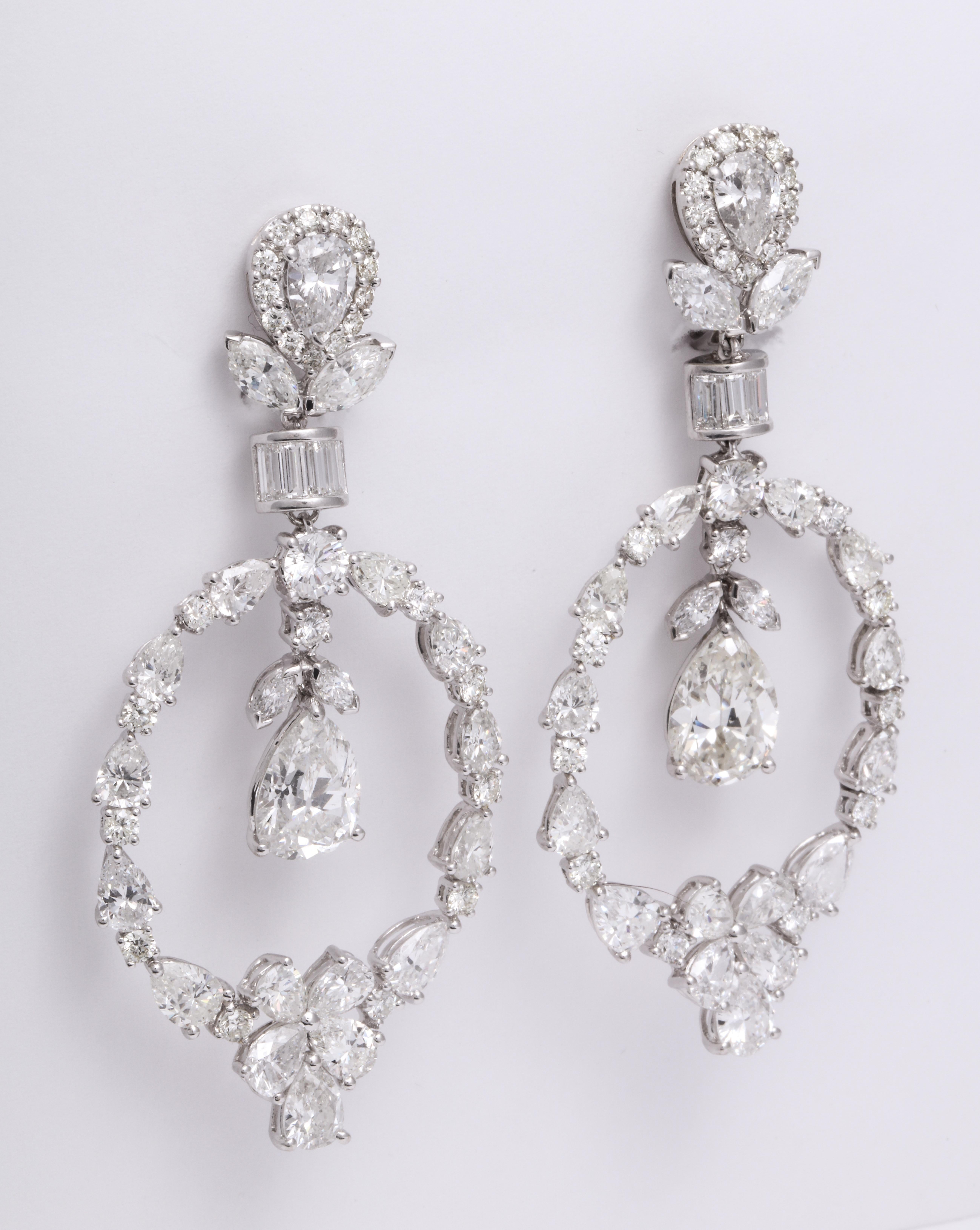 Elegant and showstopping handmade 18 Karat white gold chandelier earrings mounted with inverted pear shape diamond studs within a round brilliant-cut, marquise, and baguette diamond frame, suspending an articulating pear shape and round