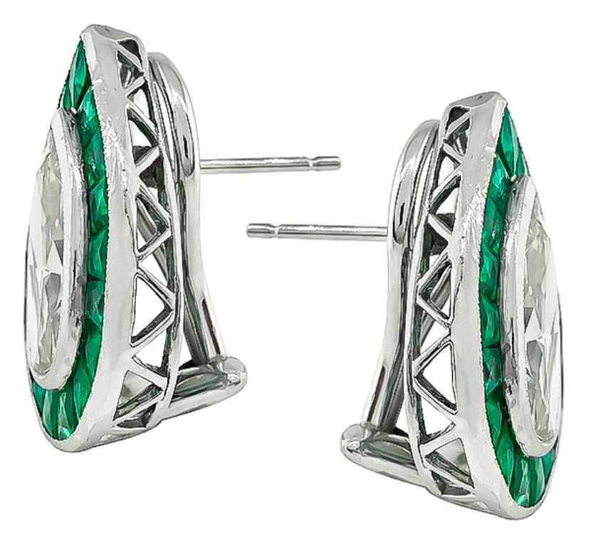 This fabulous pair of platinum earrings feature sparkling pear shape diamonds that weigh approximately 4.20ct. graded K-L color with VS2-SI1 clarity. The diamonds are accentuated by lovely French cut emeralds that weigh approximately 4.00ct. The