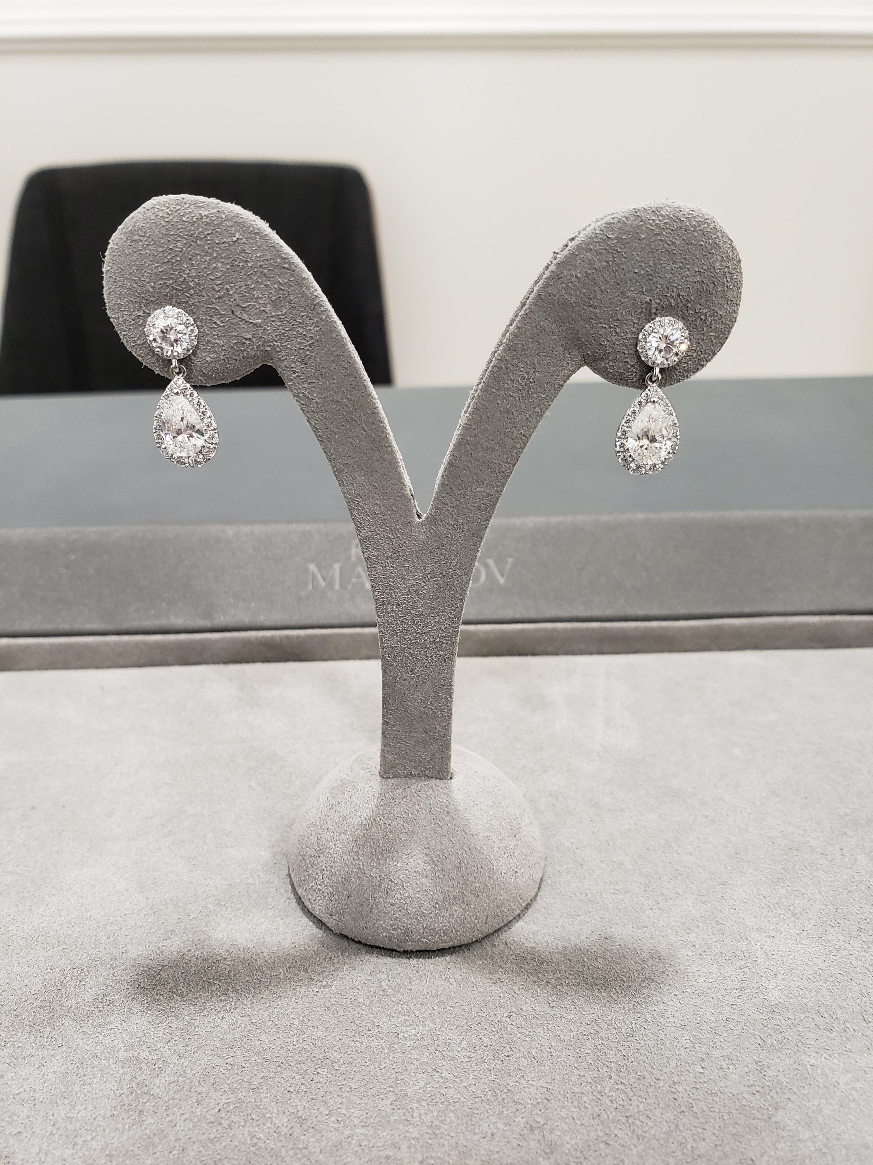 Showcasing pear shape diamond center stones weighing 1.79 carats total, surrounded by a halo of round brilliant diamonds. Suspended on a diamond encrusted post made in 18 karat white gold. Accent diamonds weigh 1.29 carats total.

