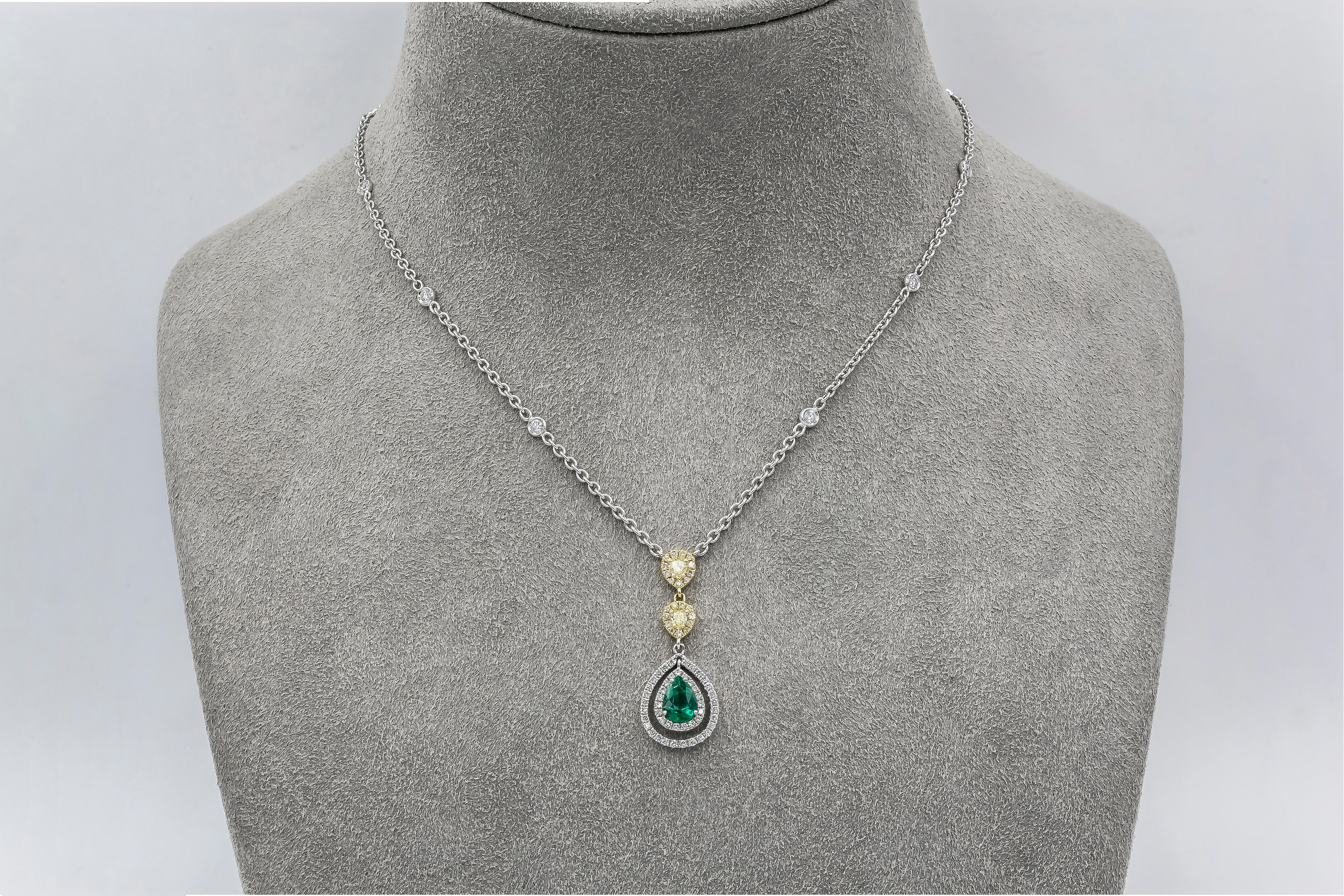 Showcasing 0.68 carat green emerald accented with two rows of round brilliant diamonds. The pendant is suspended on a two pear shape yellow diamond halos, attached to a diamonds by the yard chain. Diamonds weigh 0.58 carats total; yellow diamonds