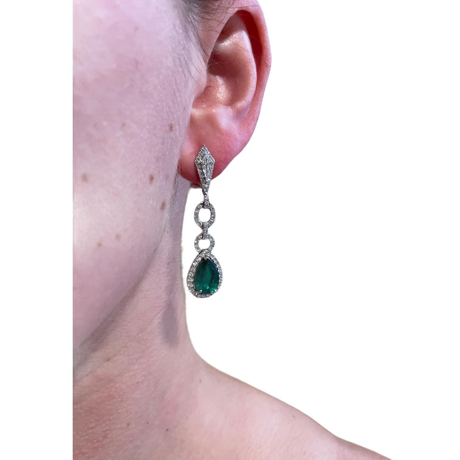 Glamorous emerald and diamond drop earrings in 18k white gold. Earrings contain 2 fine pear shape emerald drops 5.11tcw, surrounded by 134 round brilliant diamonds & 2 kite shape diamonds, 2.35tcw. Diamonds are near colorless and VS in clarity.