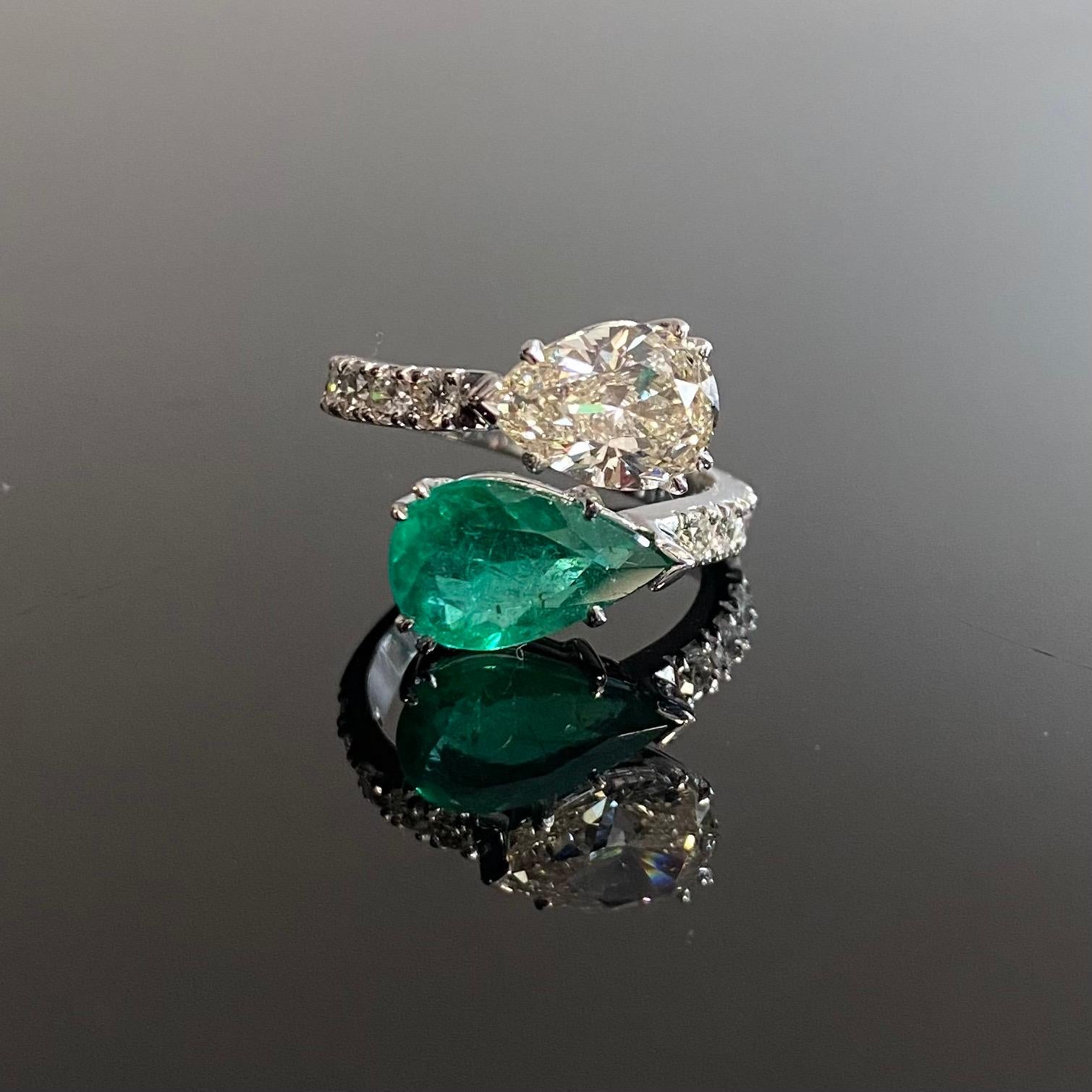 Contemporary Emerald and Diamond Toi-et-Moi Crossover Engagement Ring in 19.2kt White Gold, Portugal, 2000s. This jewel features a pear-shape emerald of a deep green color and a sparkly pear brilliant-cut diamond both talon-claw-set in open-back