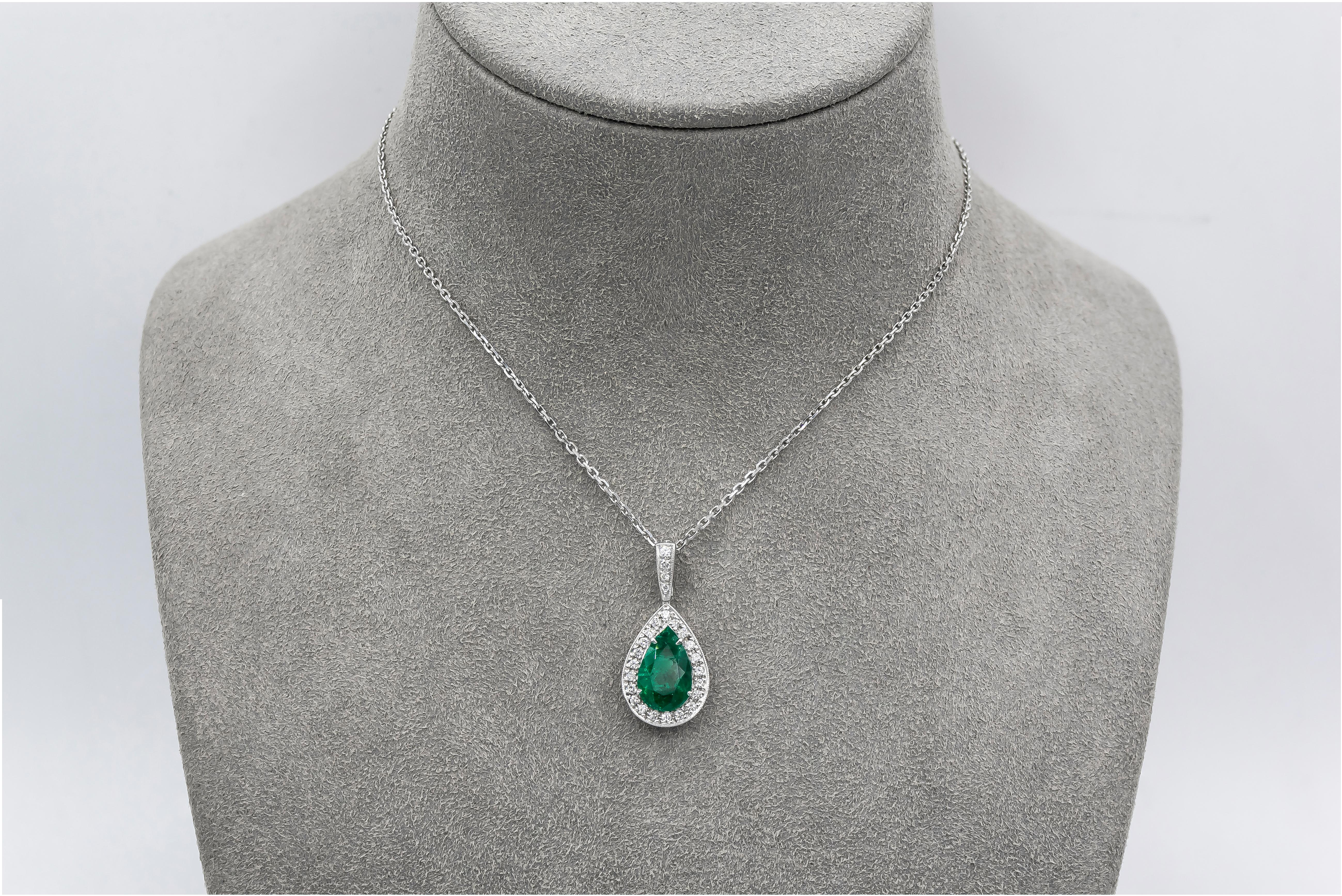 Showcasing a 1.89 carat pear shape green emerald, surrounded by a single row of round brilliant diamonds. Attached to a diamond encrusted bale, on an 18 inch white gold chain. Finished with milgrain design for an extra antique style and feel.