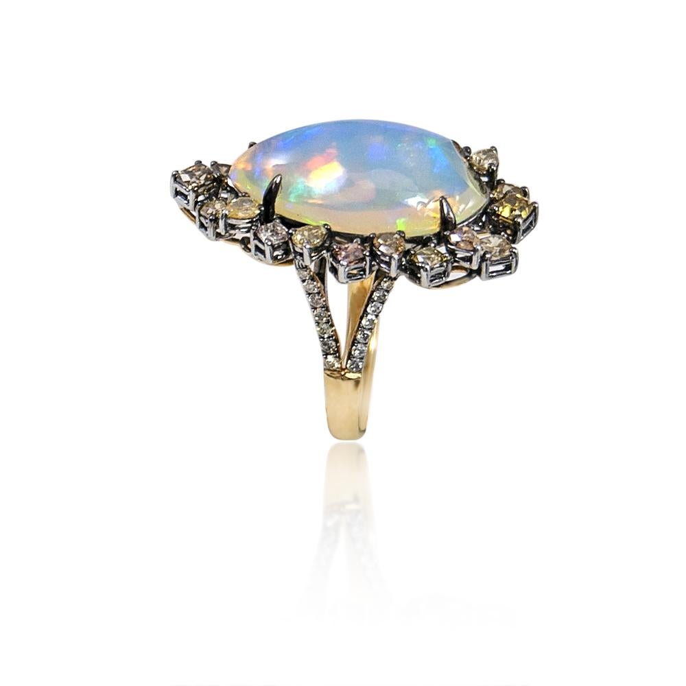 Unique and elegant statement ring features a genuine and natural 23x8mm 13.25 carat oval shaped opal with beautiful natural play-of-color luster. The opal is artfully placed in a magnificent setting of twenty fancy colored diamonds in different