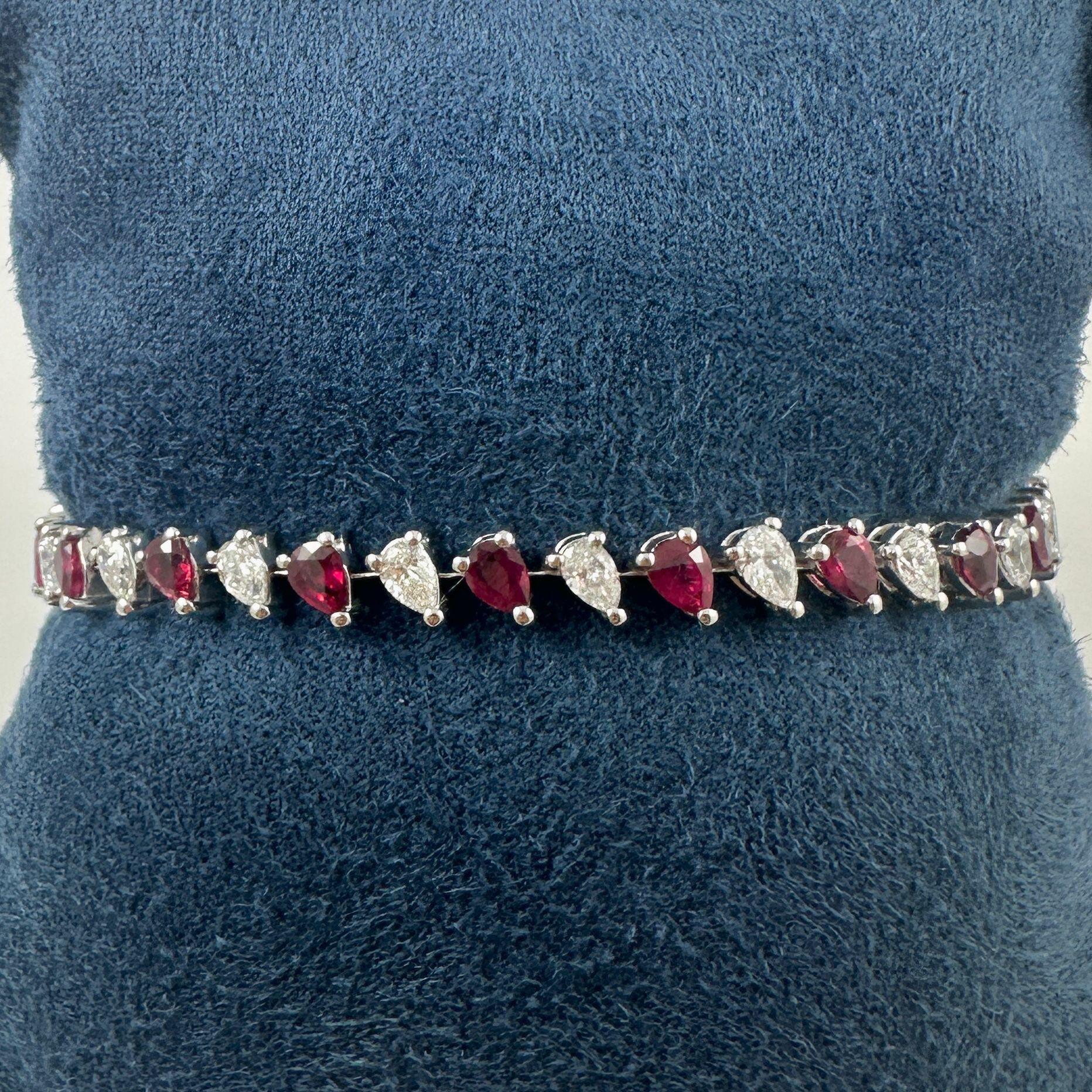 Elegant und strahlend präsentiert sich dieses exquisite Armband mit einem atemberaubenden Arrangement birnenförmiger natürlicher Rubine, die von funkelnden Diamanten im Brillantschliff akzentuiert werden. Jeder Rubin mit einem Gesamtgewicht von ca.