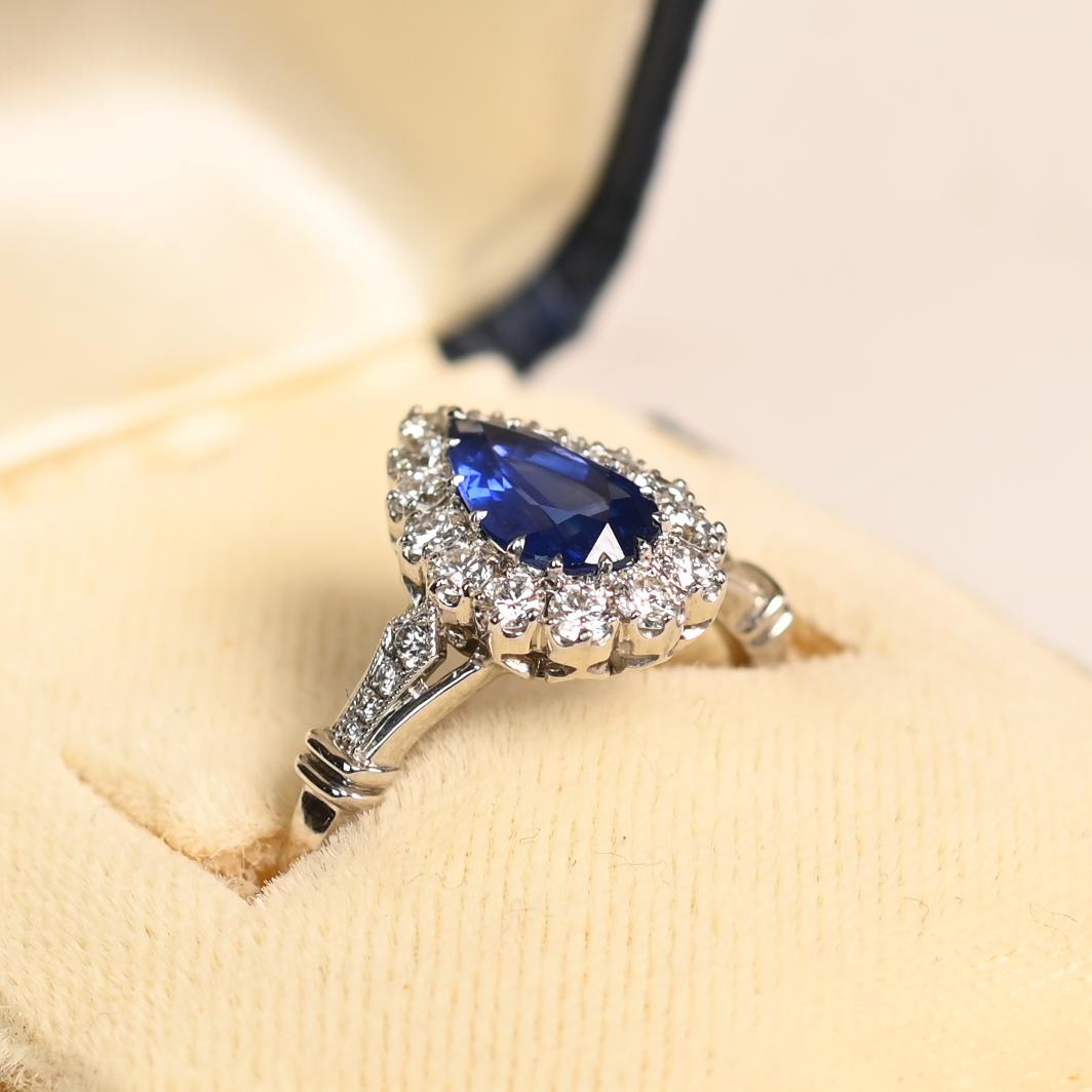 This stunning ring showcases a approx. 1.00-carat pear-shaped sapphire at its center, captivating with its deep, rich color and exceptional clarity. The sapphire is securely prong-set, allowing its natural beauty to take center stage. Surrounding