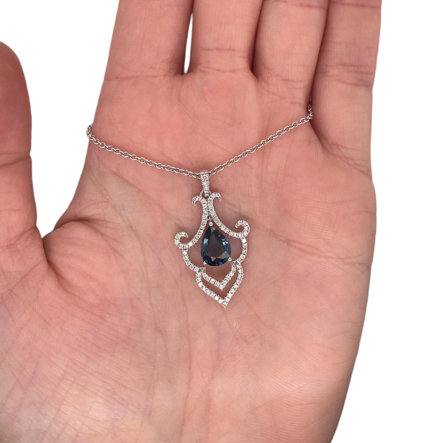 Pendant contains 1 center pear shape sapphire, 1.61ct. Sapphire dangles from a fancy halo containing round brilliant diamonds weighing a total of 0.45tcts. Diamonds are near colorless and SI1 in clarity. Pendant hangs from a 14k white gold 16