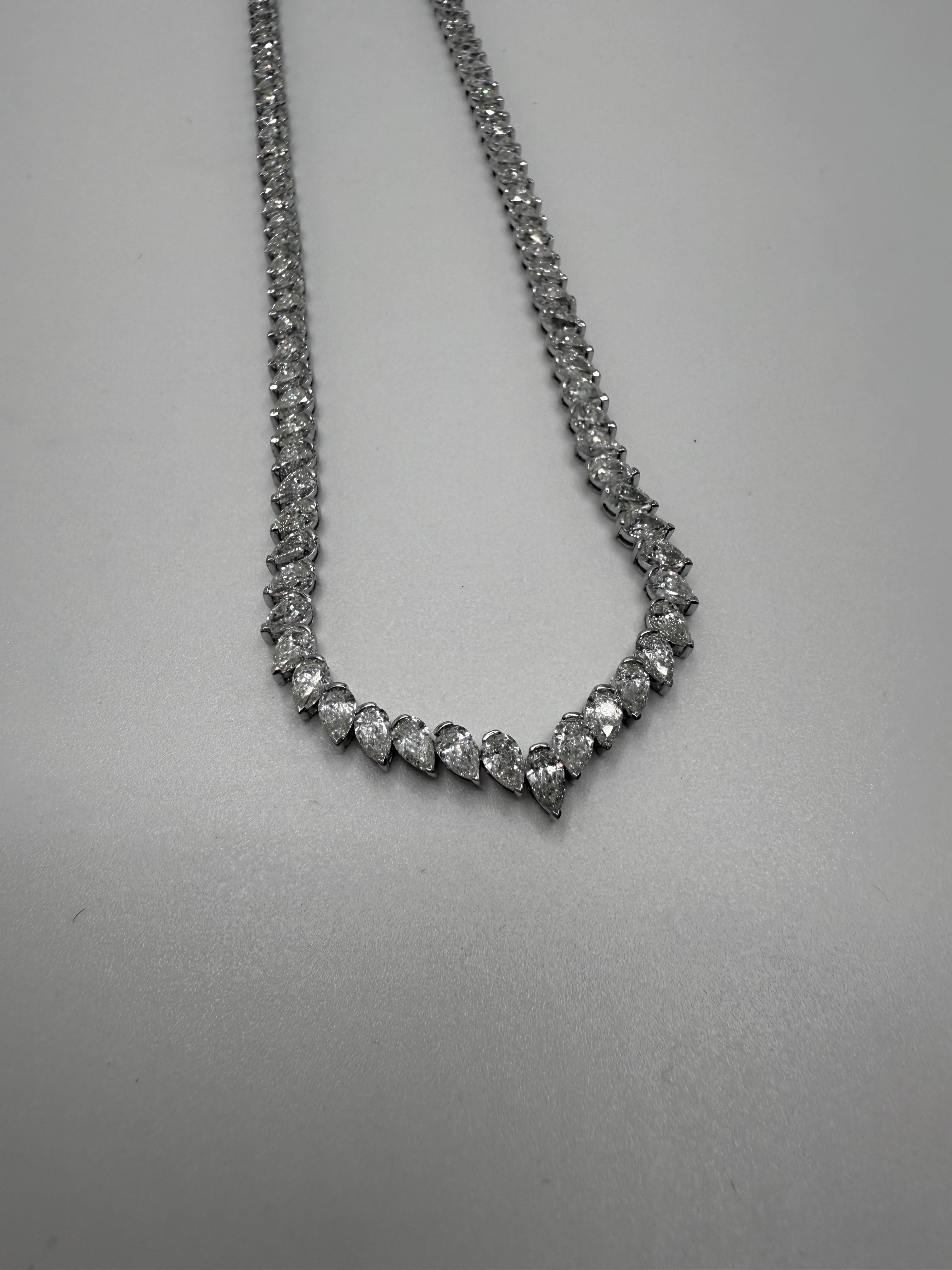 Cet élégant collier de tennis est réalisé en luxueux or blanc 18 carats et présente une ligne continue de diamants en forme de poire totalisant 13,55 carats. Chaque diamant est méticuleusement serti pour créer un flux continu de brillance, drapant