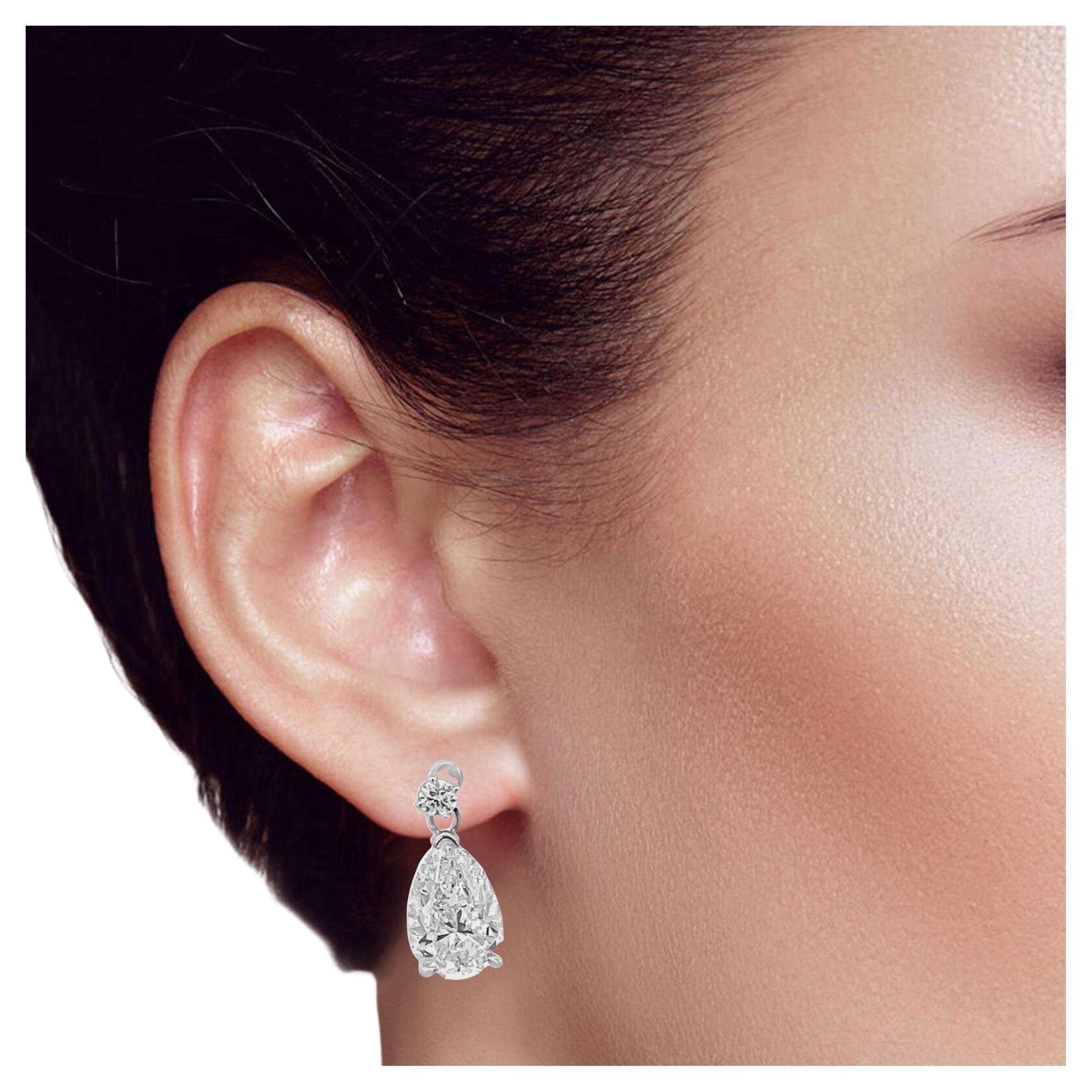 Graziosamente realizzati in oro bianco 18 carati, questi orecchini pendenti rotondi brillano con diamanti naturali di purezza G SI2. La loro eleganza senza tempo e il movimento sottile li rendono l'accessorio perfetto per ogni