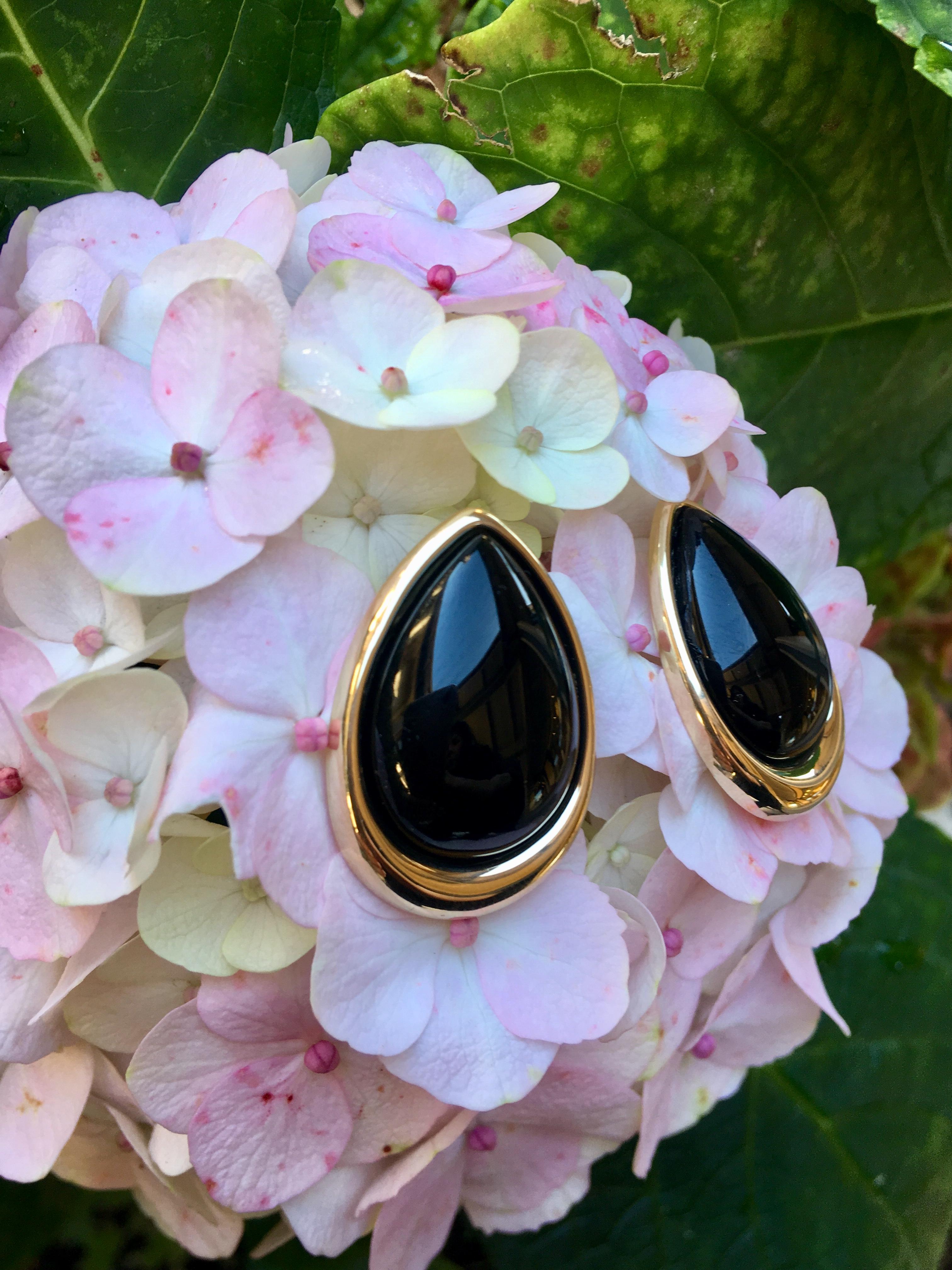 Modernistic, elegant, large, pear shaped, rounded black onyx stones are bezel set in highly polished 14 karat yellow gold, with posts and friction backs for pierced ears. Well designed and well made, these earring feature posts which are nicely