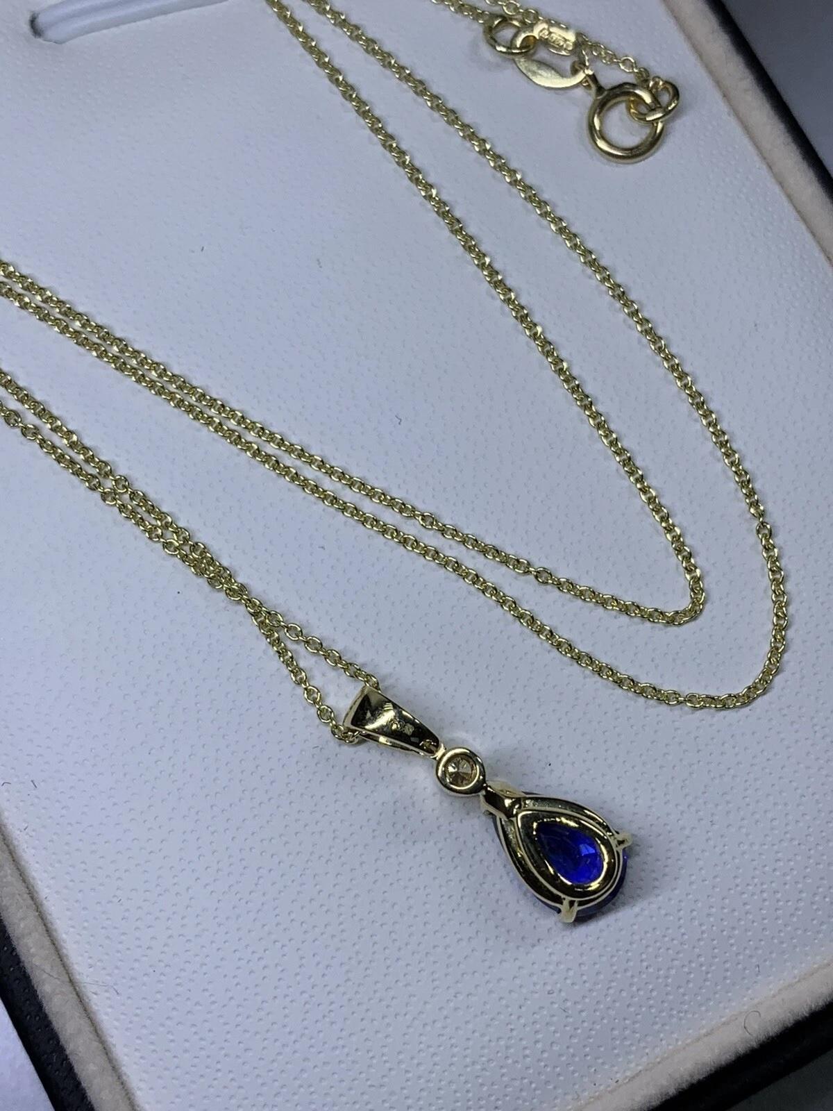 This stunning necklace boasts a beautiful pear-shaped natural blue sapphire as the main stone, surrounded by sparkling diamonds. The pendant sits on a luxurious 18ct yellow gold chain for a truly elegant look. The necklace has a solitaire setting