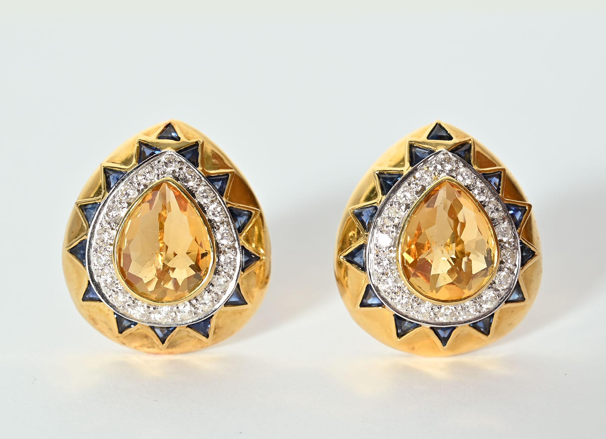 Bold pear shaped 14 karat gold earrings centered with  citrine stones that are approximately 10 mm each. Around the citrines are 35 round brilliant cut diamonds that are .9 carats in weight; G color and SI 1`2 clarity. Triangular shaped sapphires