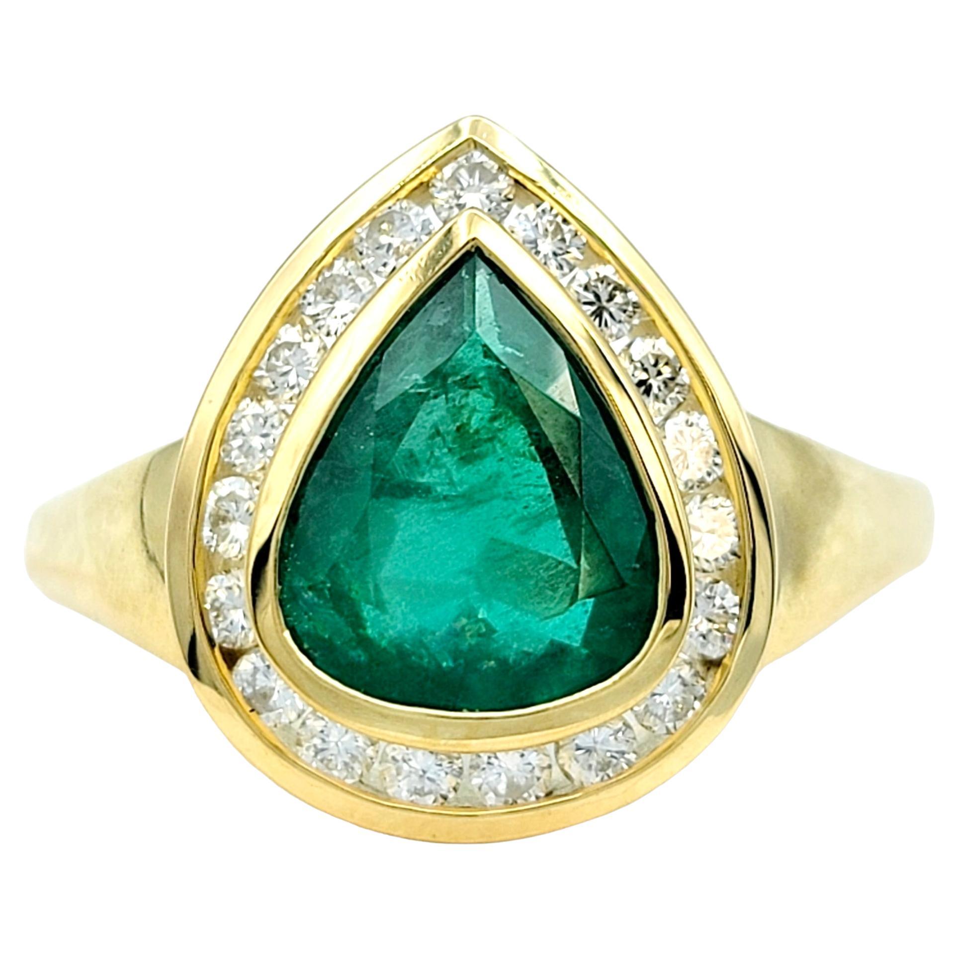 Ring size: 9.25 

This elegant emerald ring, beautifully set in 18 karat yellow gold, is a striking piece with timeless beauty and bold color. The centerpiece, a lustrous pear-shaped emerald, rests securely within a bezel setting. Surrounding the