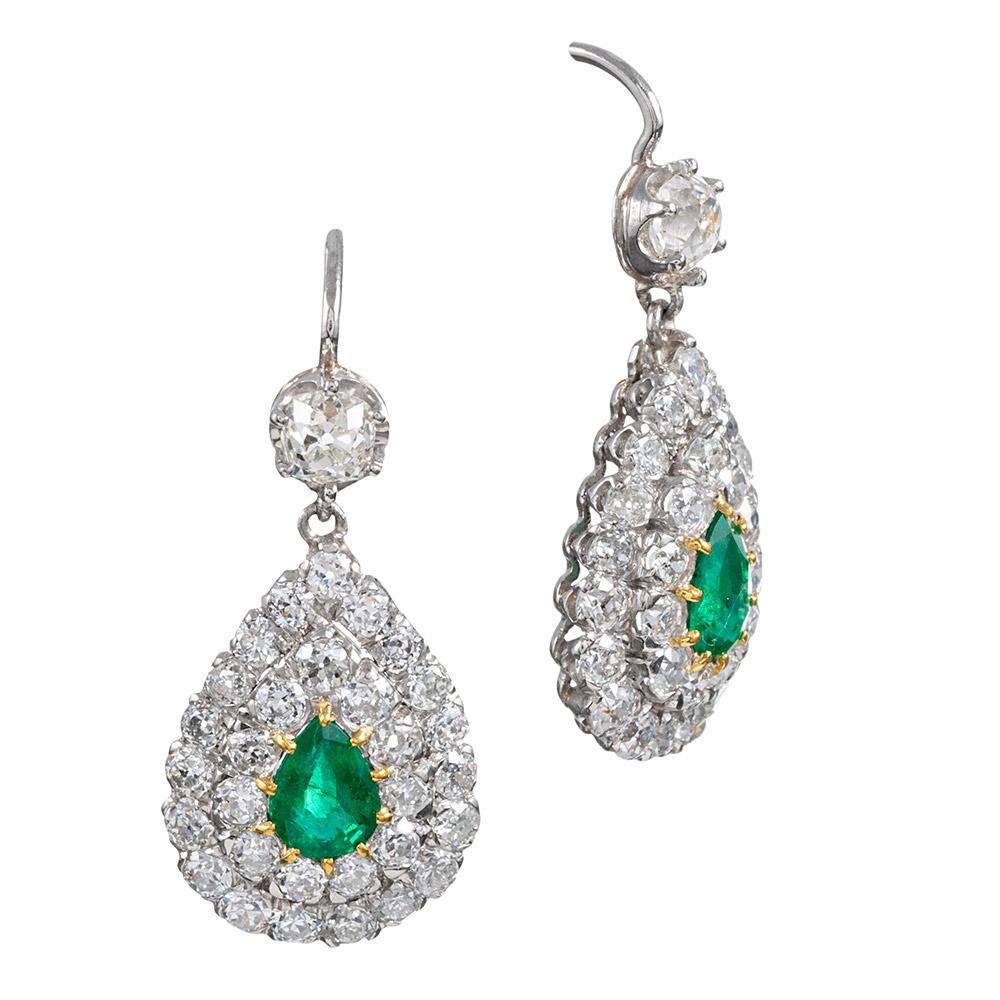 Rendered in platinum with 18 karat yellow gold lever backs, the earrings combine the charm of antique cut diamonds with emeralds of exceptional quality, resulting in a glorious display of artful craftsmanship. The pair of larger old mine cut
