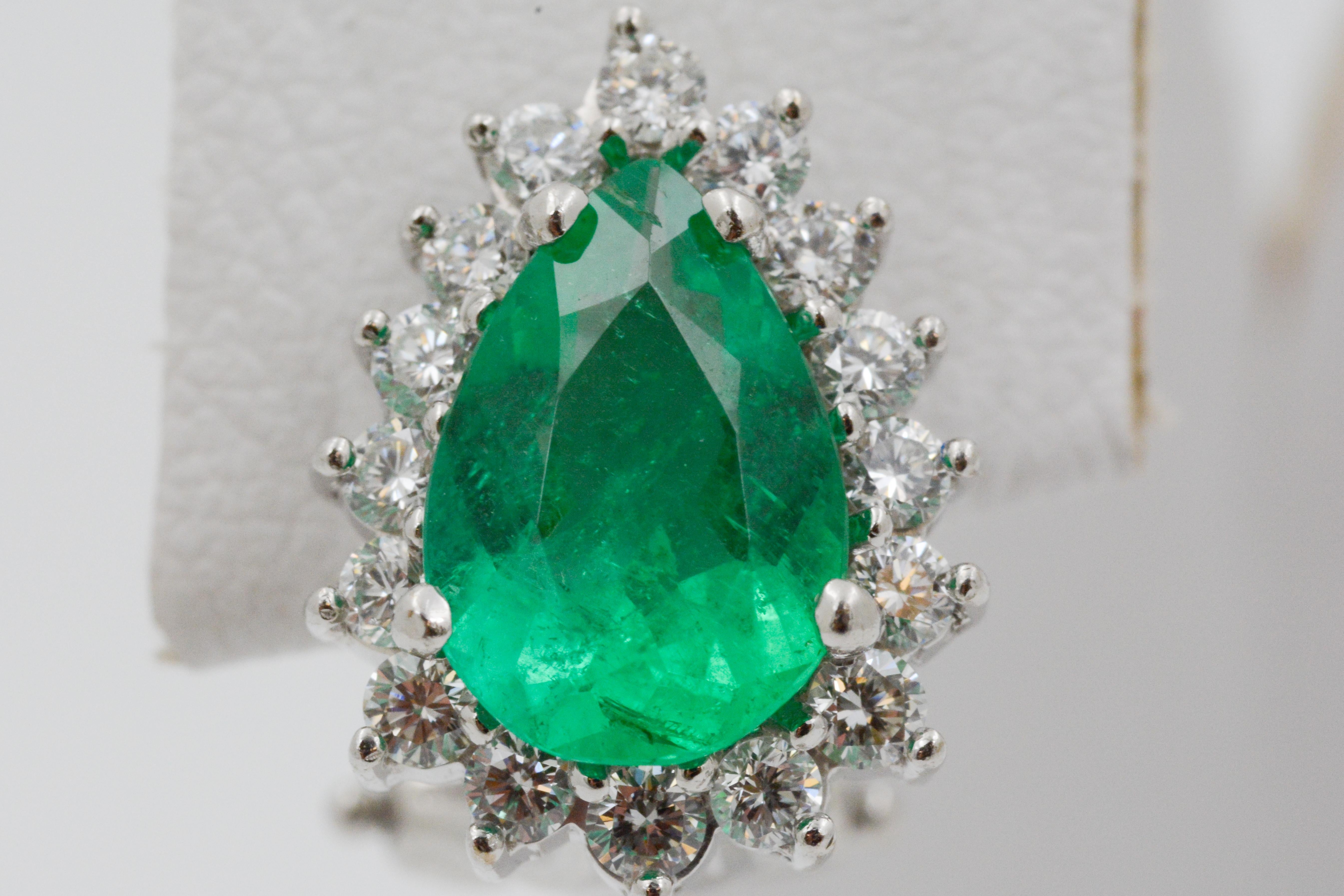 These vibrant 18k white gold earrings feature two pear shaped emeralds, weighing a total of 2.72 carats. 32 round diamonds, weighing a total of .32 carats with G coloring and VS clarity, surround the emeralds. The earrings have omega post backs.  