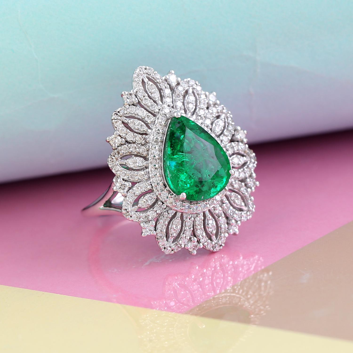 This exquisite ring features a stunning pear-shaped green emerald, surrounded by a sparkling array of diamonds, all set in 18k white gold. The emerald, with its deep green hue, is beautifully complemented by the brilliant diamonds, which enhance the