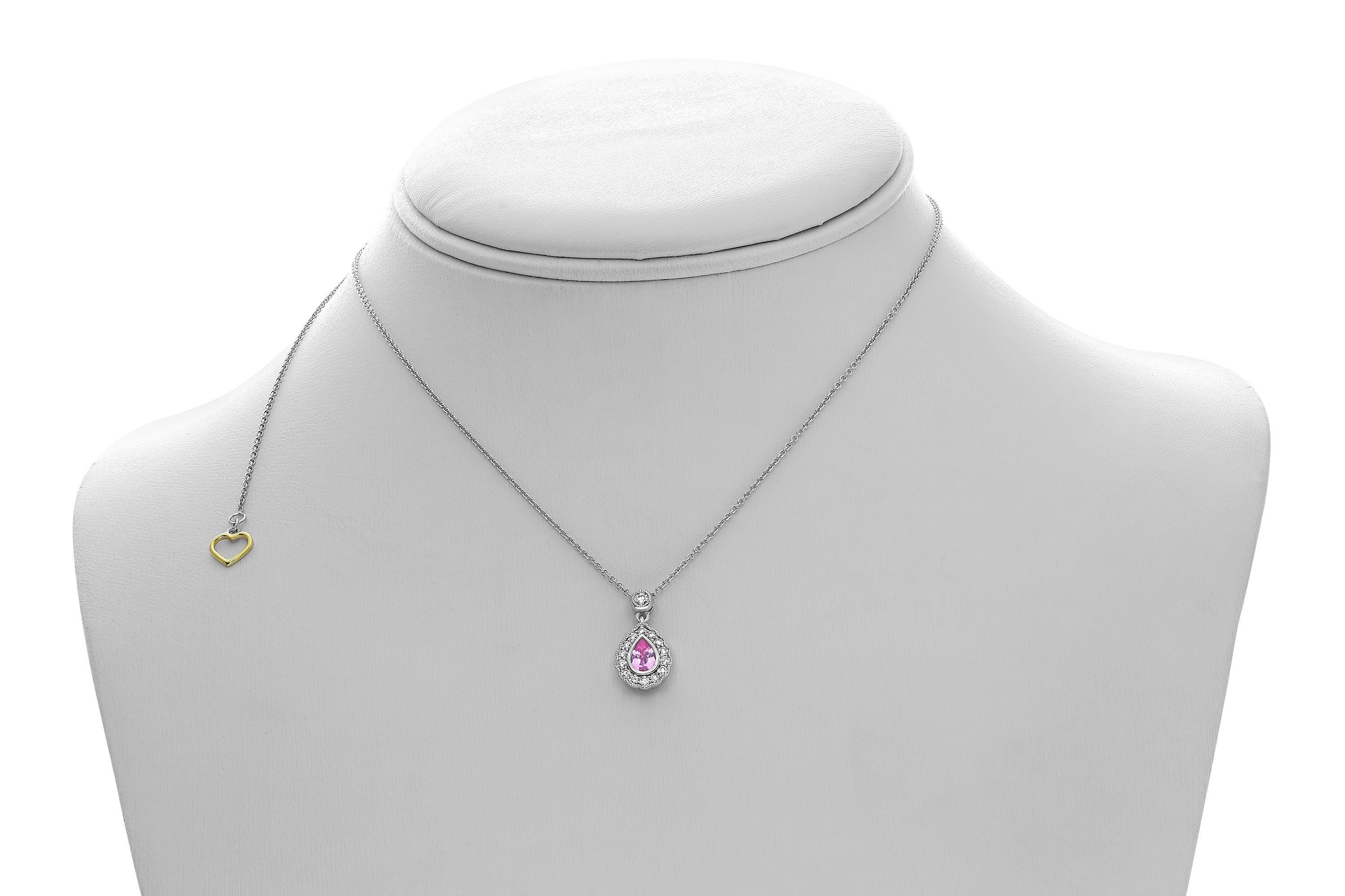 This 18 karat white gold necklace showcases a 0.47 carat, pear-shaped pink sapphire accented by 0.25 carats of round cut white diamonds showcased in a stunning single halo ornamented by intricate milgrain detailing. 

The center stone is eye clean
