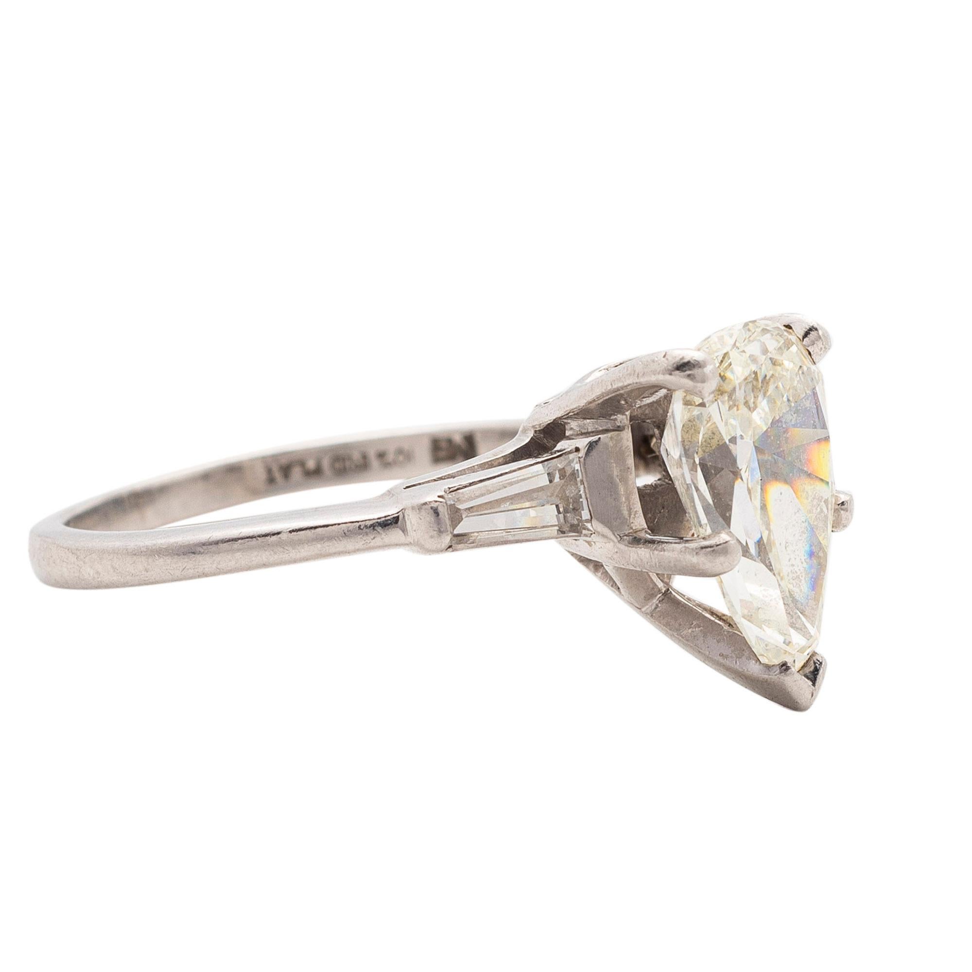 Diamond Ring
Centering a pear-shaped diamond weighing approximately 2.30 carats, on a raised mount highlighted with fluted shoulders flanked by tapered baguette diamonds, mounted in Platinum, size 5.