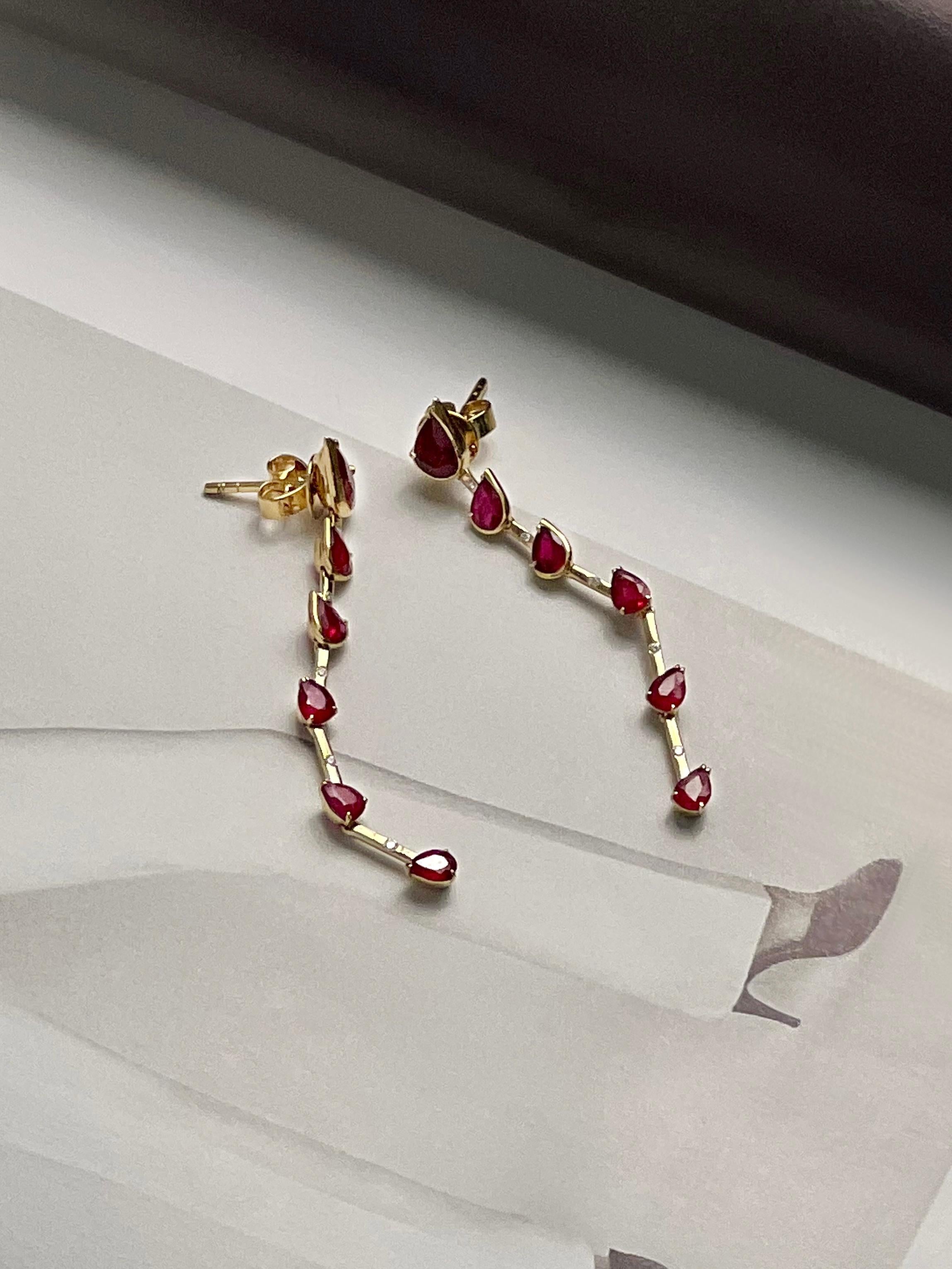 These stunning pear shaped ruby drop earrings are crafted in luxurious 18k yellow gold. The lustrous gold frames the vivid and eye-catching rubies, separated by small diamonds. The rubies are cut in a unique pear shape totalling 2.84cts. They add an