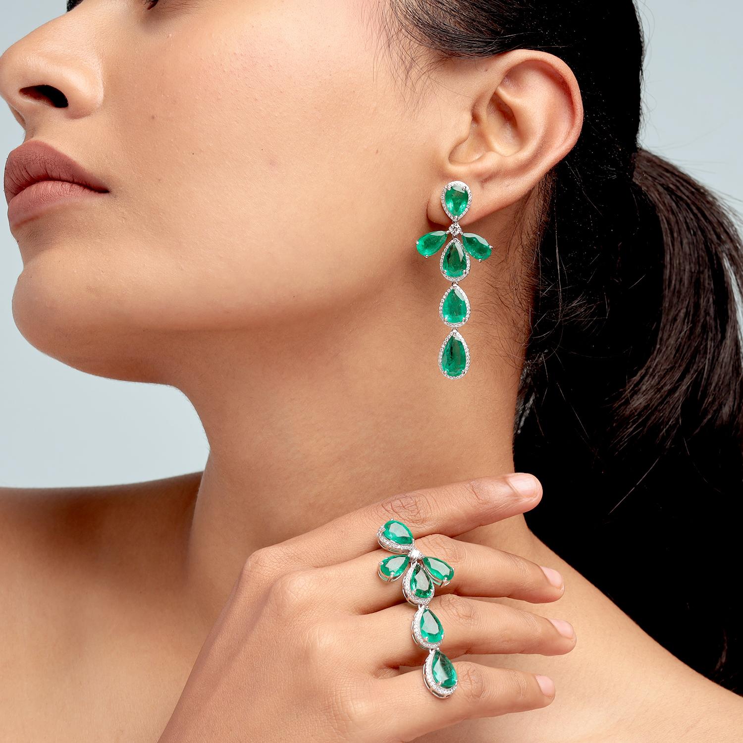 Gracieuses et saisissantes, ces boucles d'oreilles pendantes à plusieurs tiges présentent de luxuriantes émeraudes de Zambie en forme de poire totalisant 21,42 carats, élégamment encadrées par 1,26 carat de diamants étincelants. Fabriquée en or 18