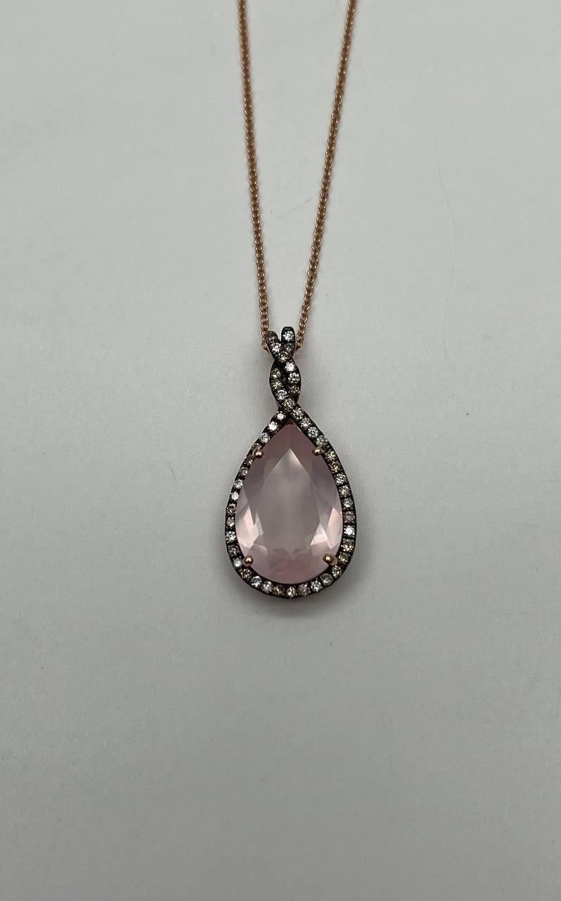 Questa squisita collana con ciondolo presenta un quarzo rosa a forma di pera, elegantemente incorniciato da un'aureola di piccoli diamanti scintillanti. Il ciondolo è appeso a una delicata catenina, con una coda tempestata di diamanti che aggiunge