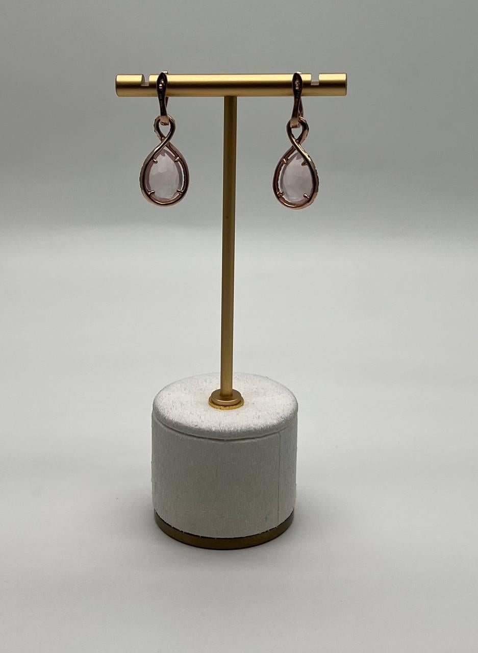 These exquisite earrings feature elegant teardrop-shaped pink rose quartz, delicately encased in a dark, sparkling diamond border. The design is completed with a graceful loop, adding a touch of sophistication. 14K Rose Gold. 0.85 CTW Diamonds. 9.40
