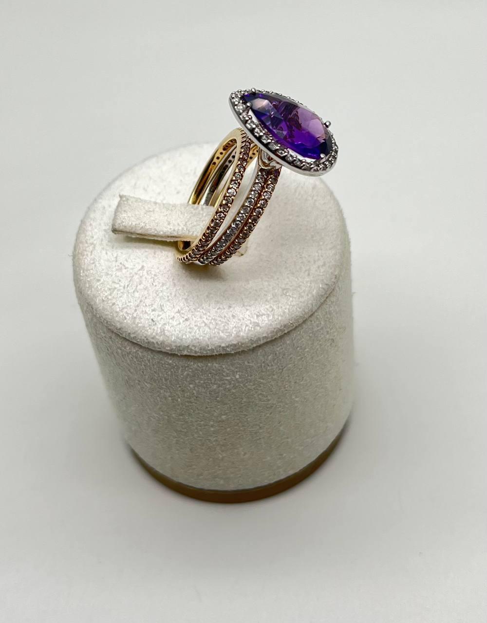 Questo elegante anello presenta una straordinaria ametista viola a forma di pera, circondata da un'aureola di scintillanti diamanti bianchi. La fascia è composta da tre file che aggiungono un effetto a strati unico. Oro giallo e bianco 14K. Diamanti