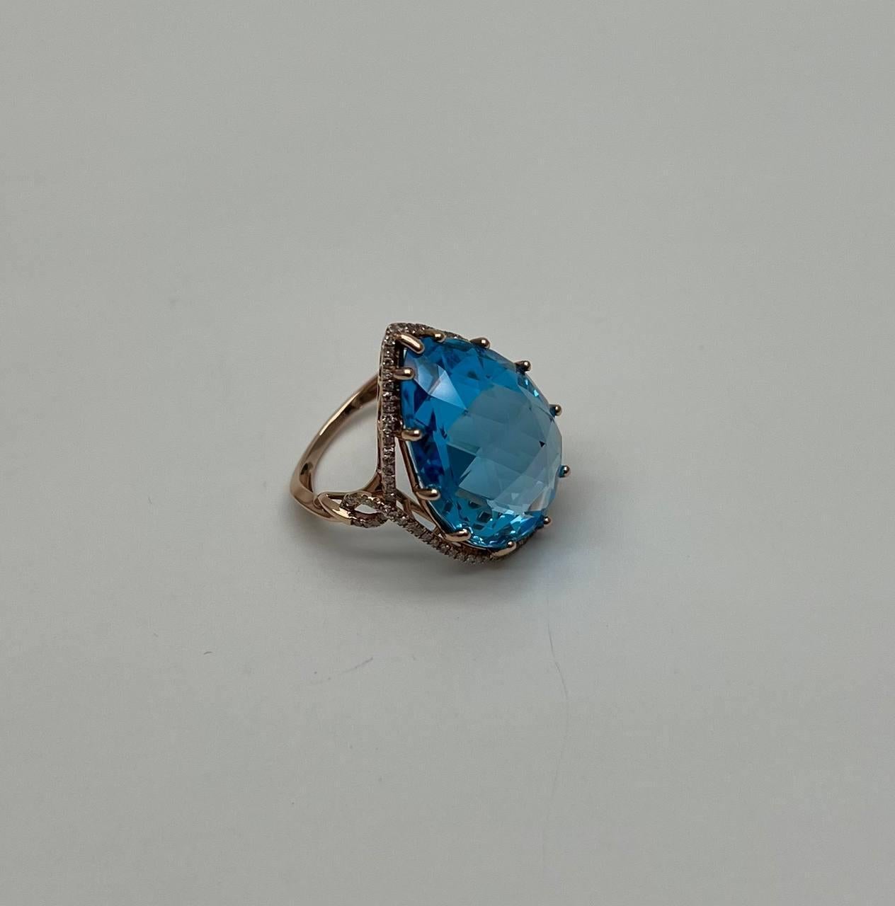 Un anillo llamativo, esta cautivadora pieza presenta una impresionante gema de topacio azul suizo en forma de pera. La piedra está engastada en una delicada garra que acentúa su vibrante color y brillo. Un halo de brillantes diamantes acentúa el