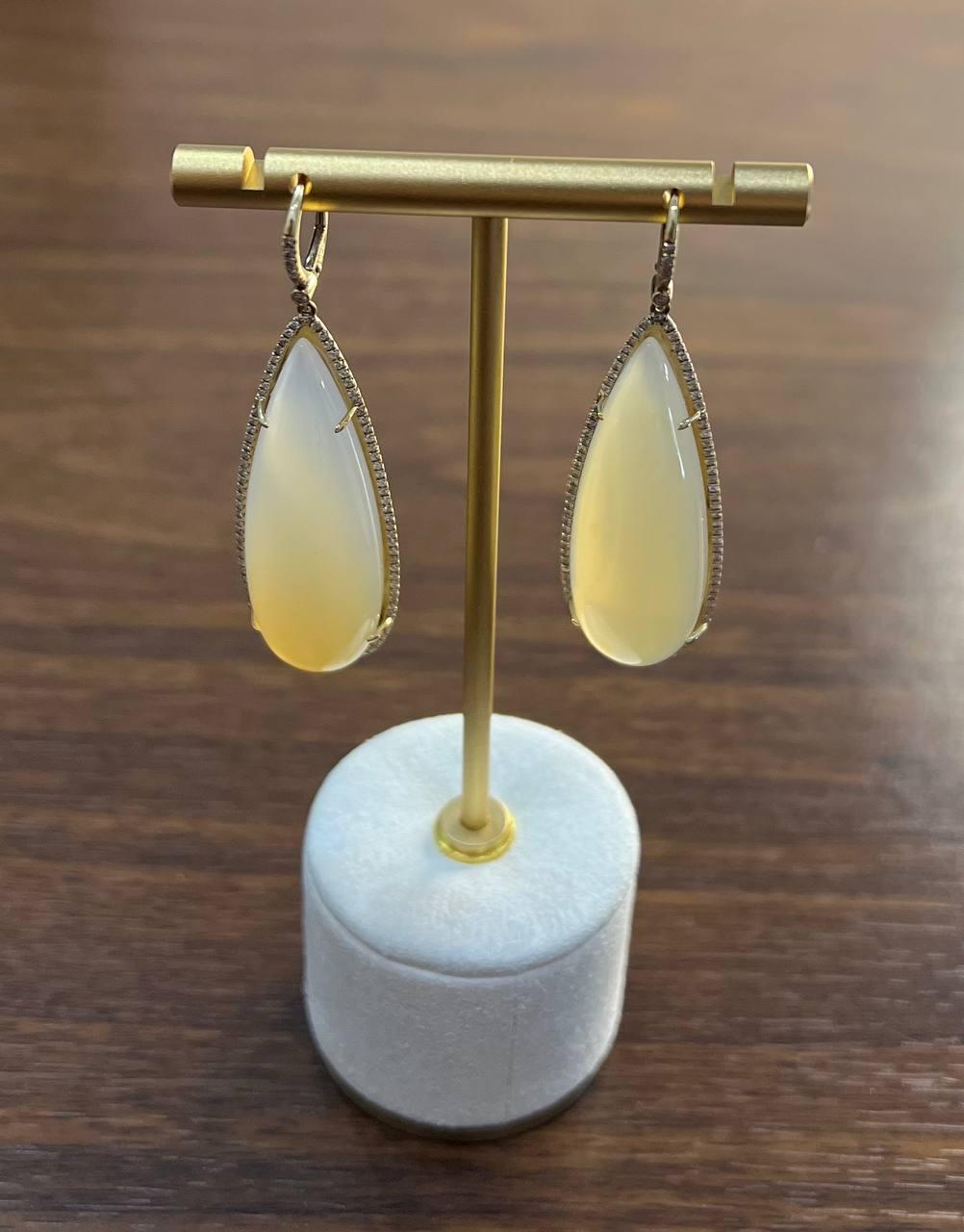 Elegant 14k Gold Diamond and Moonstone Drop Earrings. These exquisite earrings feature smooth, teardrop-shaped stones, each surrounded by a delicate halo of sparkling diamonds. The opals are set in a sleek 14k gold frame, enhancing their natural