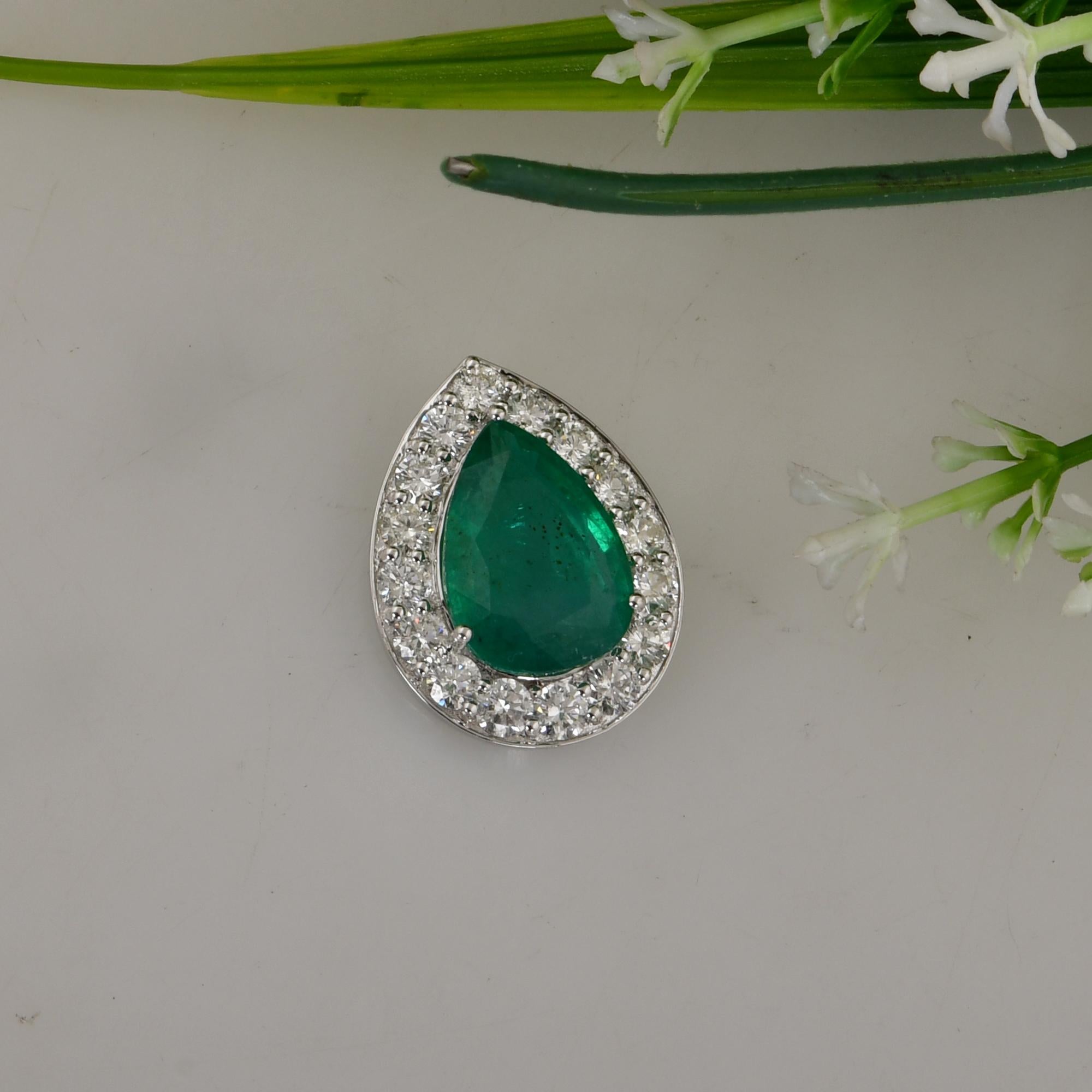 At the heart of this captivating pendant is a mesmerizing pear-shaped Zambian emerald, prized for its rich green hue and exceptional clarity. Sourced from the renowned mines of Zambia, this emerald possesses a natural beauty and allure that is truly