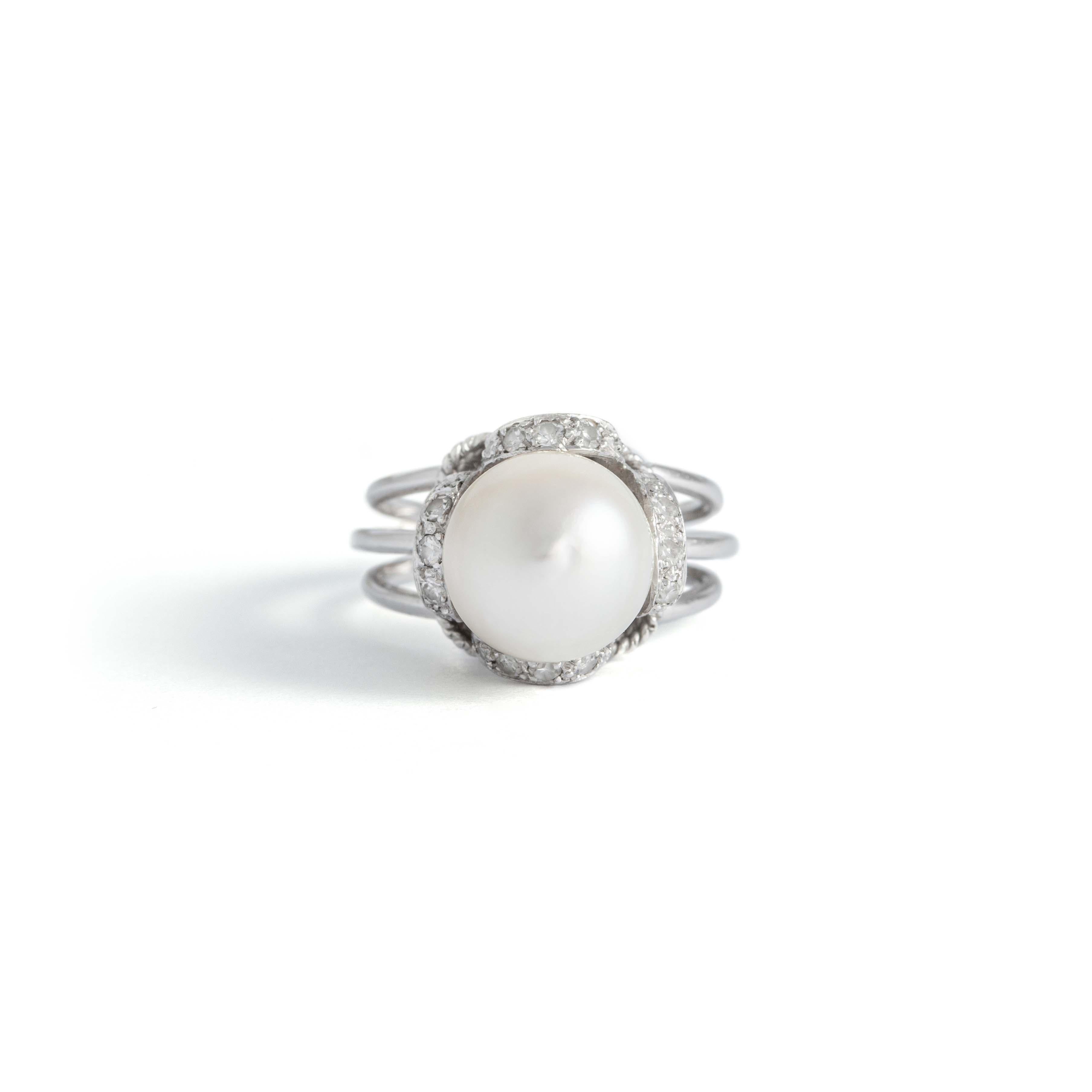 18K white gold ring centered by a cultured pearl surrounded by round-cut white stones.
Gross weight: 8.01 grams.