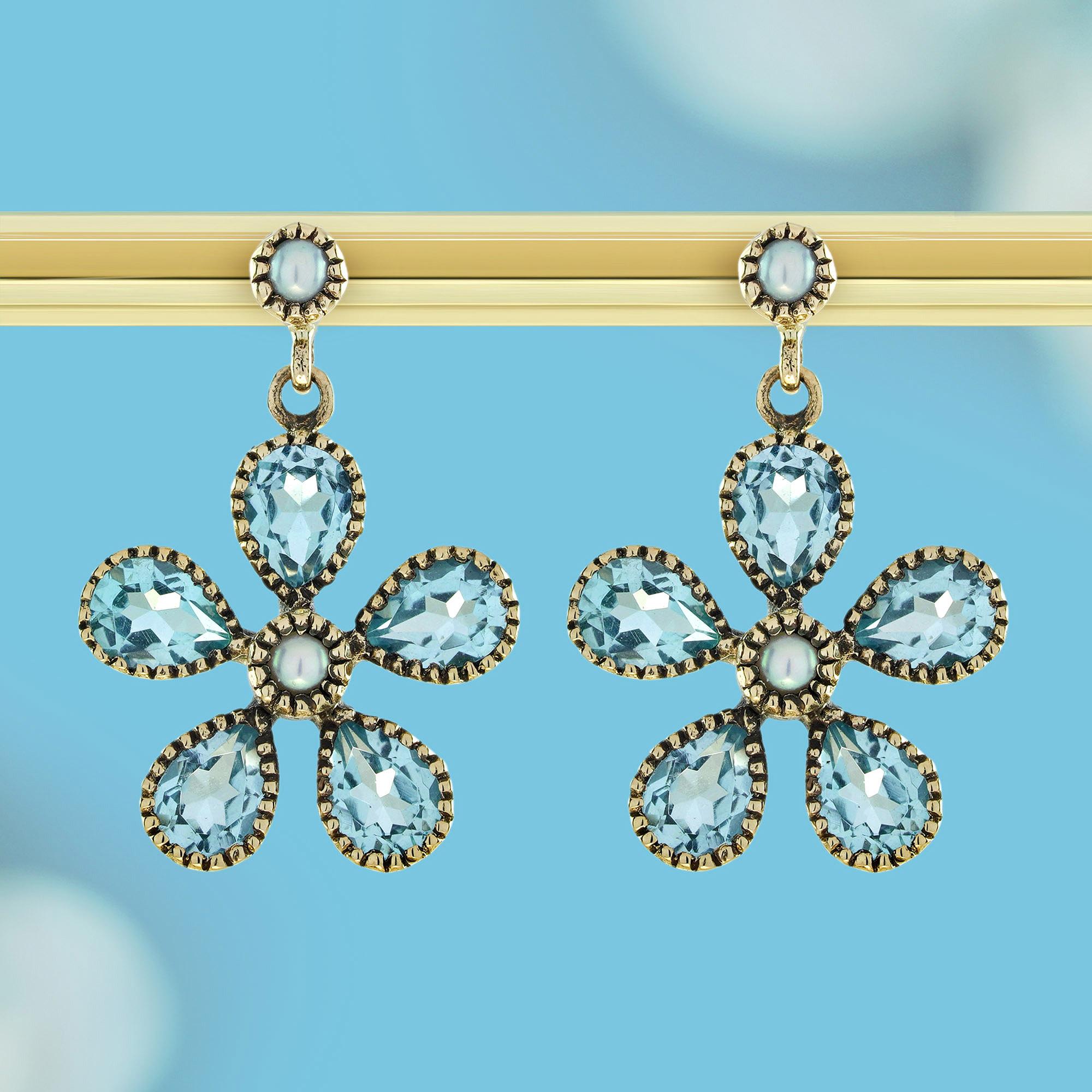 Discover the allure of these Natural Pearl and Blue Topaz Floral Dangle Earrings in 9K Yellow Gold, where classic beauty meets graceful design.Featuring luminous natural pearls that exude sophistication and radiant blue topaz gems that sparkle with