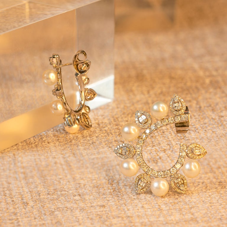 These stunning hoop earrings are decorated with alternating pear shaped diamond clusters and pearls fitted along a fine diamond set swirl. Each piece is set with five white cultured pearls measuring 5.5mm, bringing a beautiful elegance to the