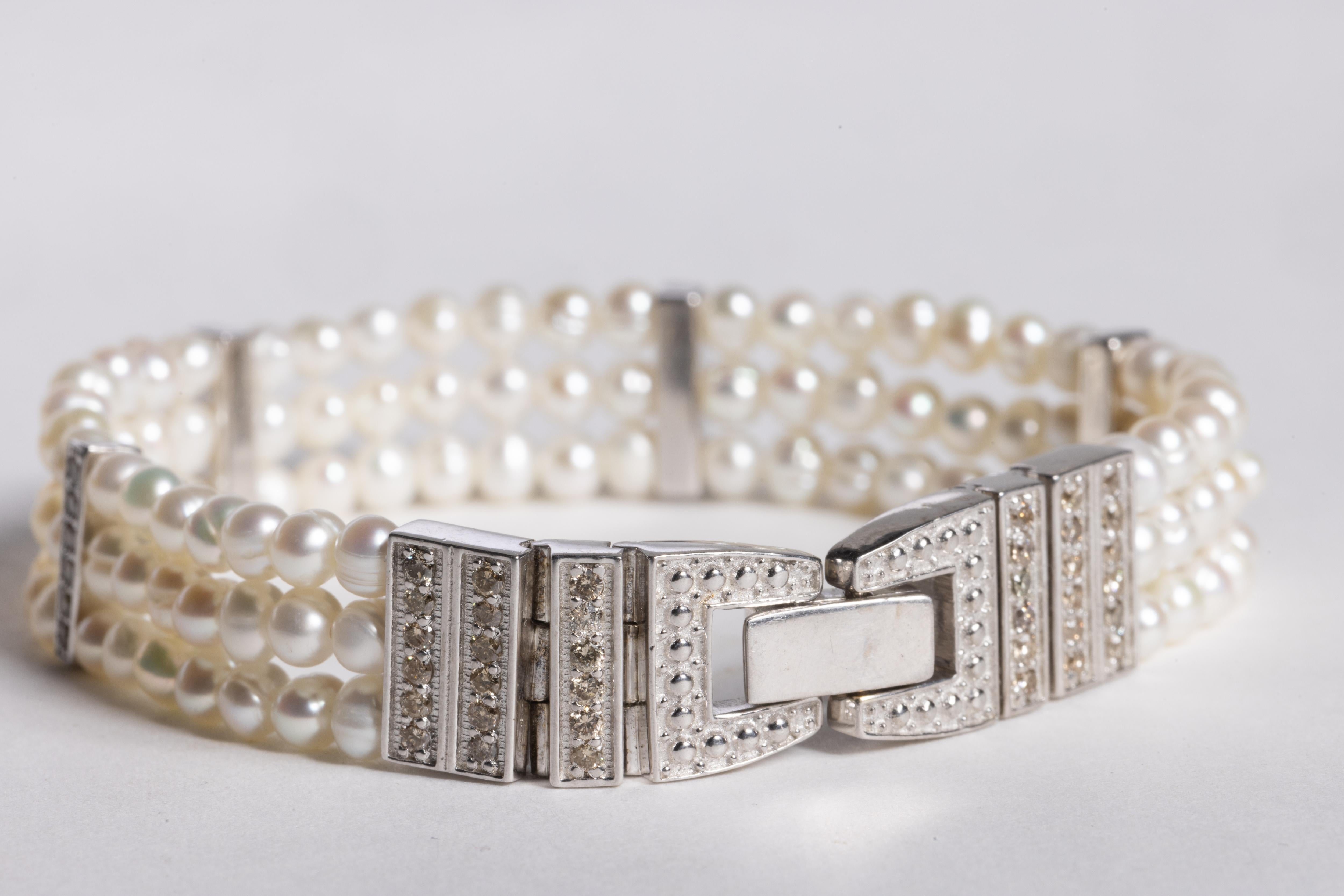 Ein dreisträngiges Perlenarmband mit 4 Diamantstäben zwischen den Perlen und einem Schnappverschluss aus Sterlingsilber und Diamanten.  Perlen insgesamt 39,50 Karat, Diamanten insgesamt 1,11  Der Innenumfang beträgt 7
