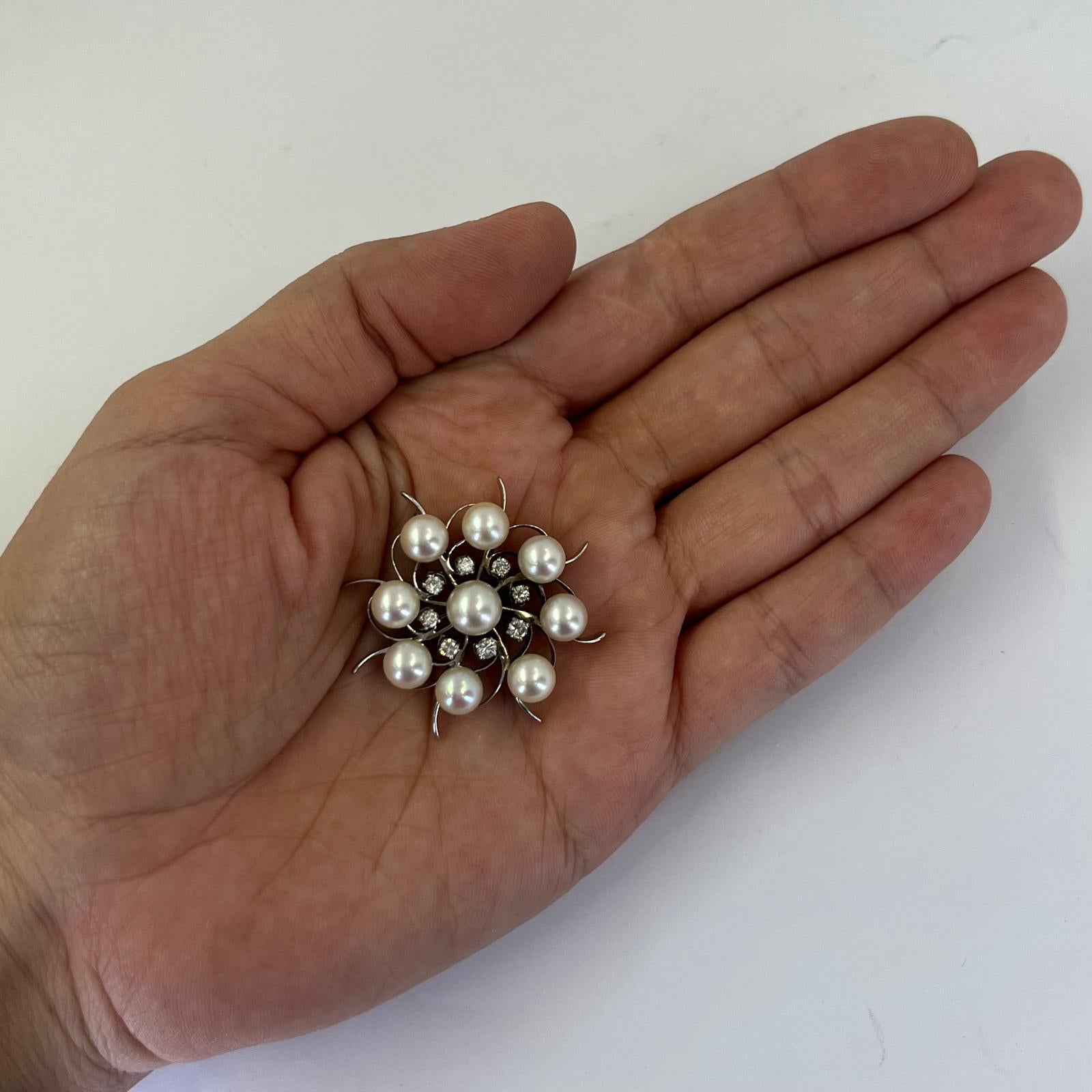 14 karat white gold circular brooch featuring 8 round brilliant cut diamonds of VS clarity and H color totaling approximately 0.50 carats accented by 9 cultured pearls measuring 6-7mm. 1.5 inch diameter. Finished weight is 11.7 grams.