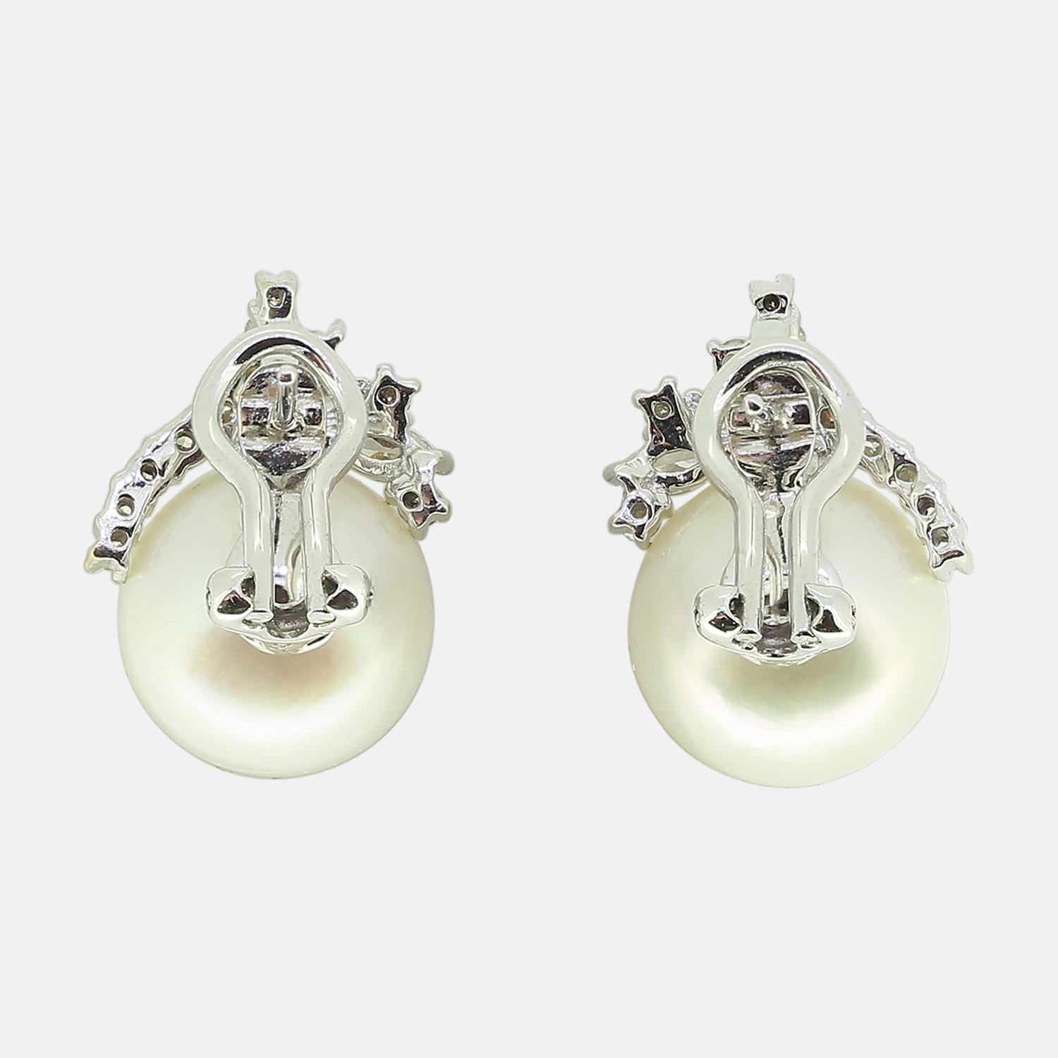 Here we have a finely crafted pair of pearl and diamond cluster earrings. Both identical pieces feature a single lustrous white pearl as the primary stone, elegantly accented by an array of sparkling white marquise and round brilliant cut diamonds