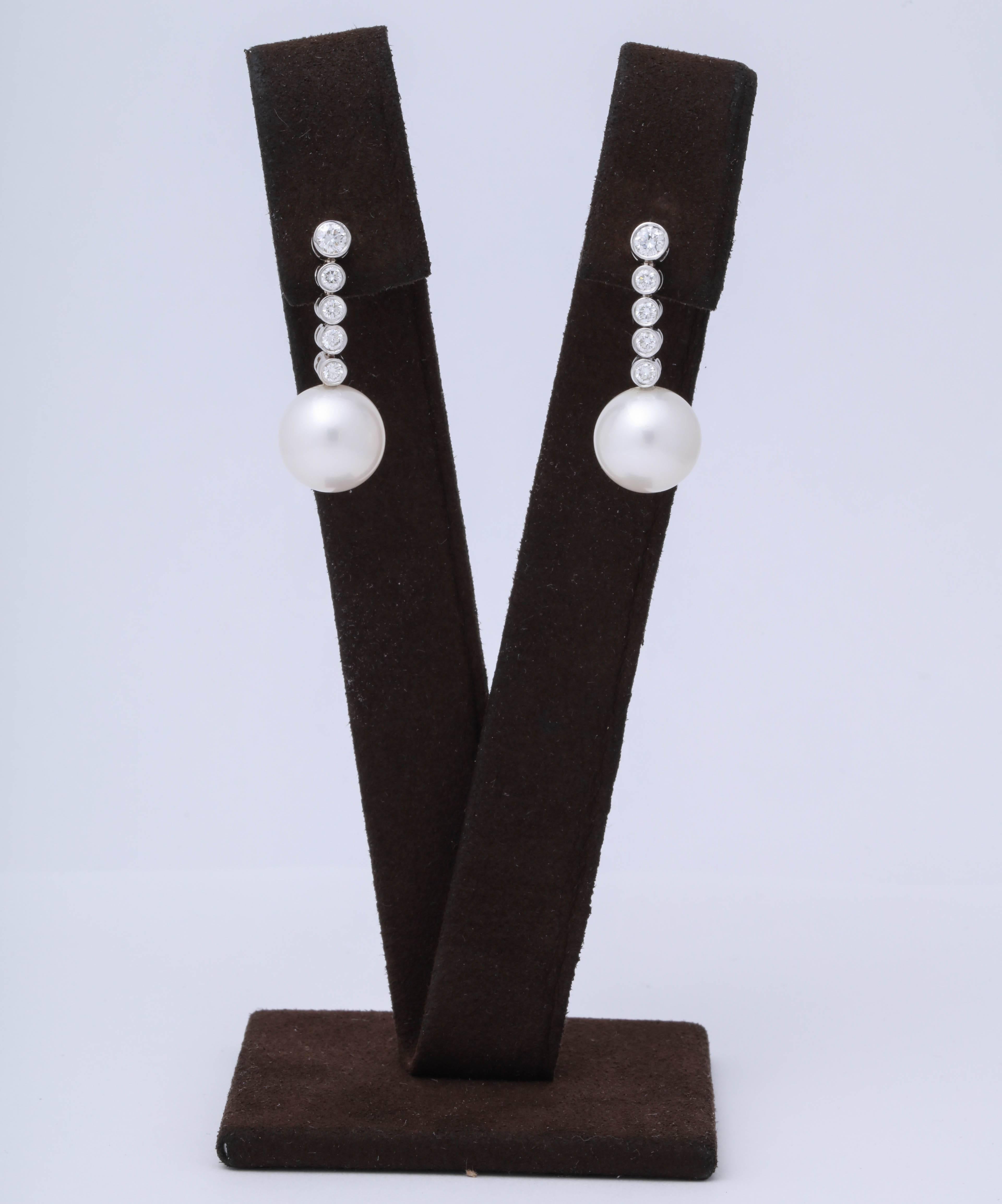 
A timeless pair of pearl and diamond dangle earrings.

.65 carats of round brilliant cut diamonds set in white gold bezels. 

11mm pearls 

18k white gold 

Just over an inch in length