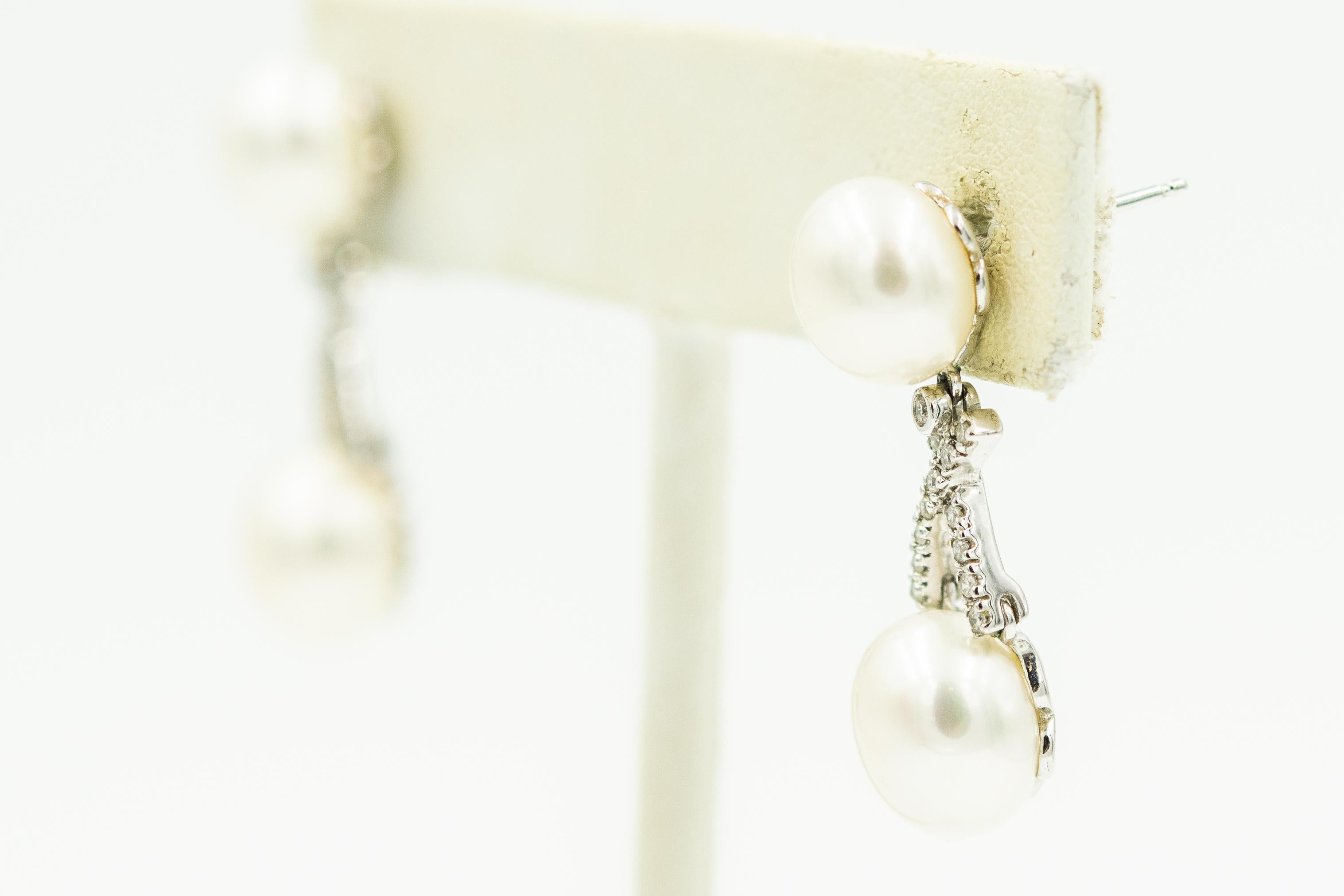 Elegant 14k white gold dangling drop earrings featuring a 9.3 mm white button cultured pearl stud with a diamond 