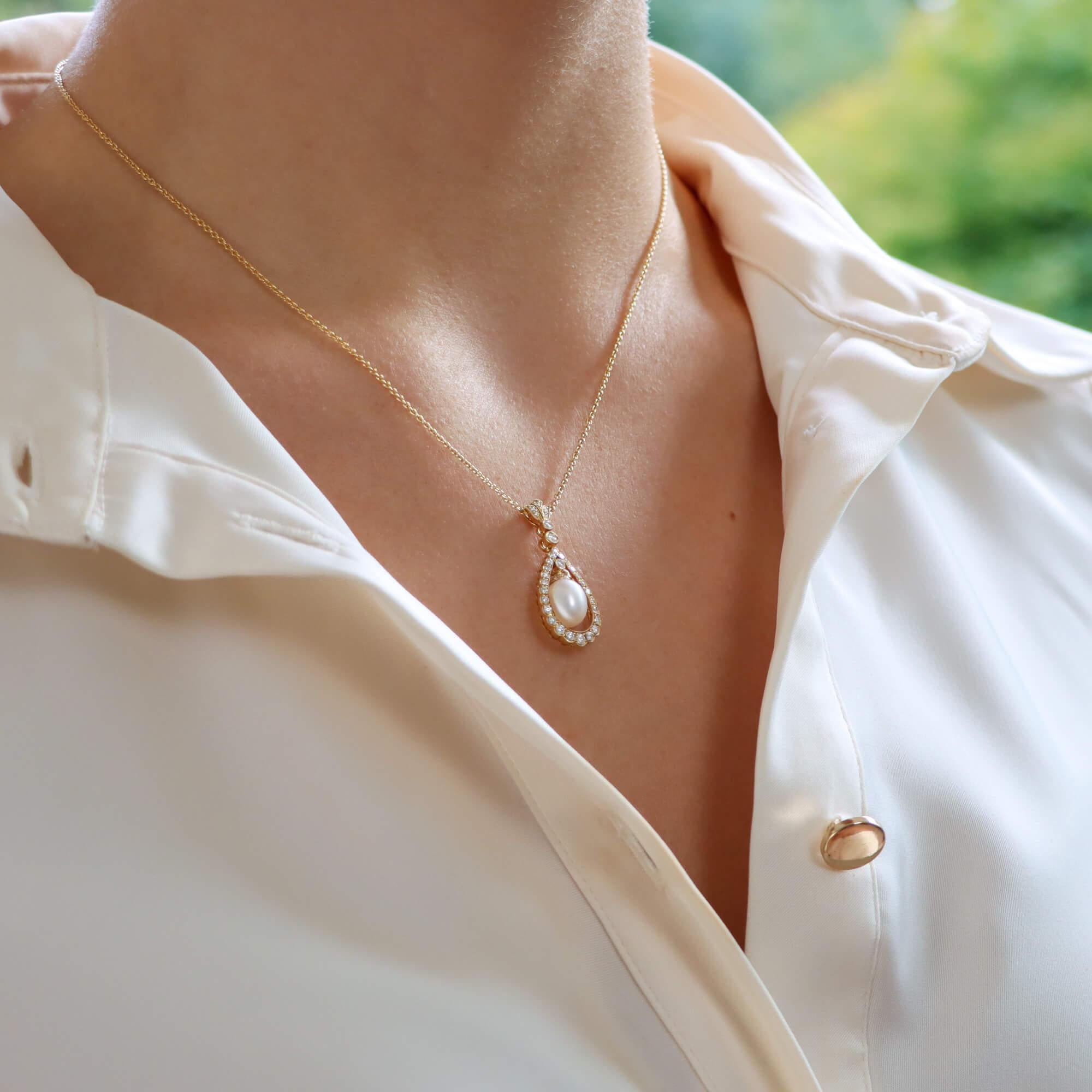 A fabulous cultured pearl and diamond garland pendant necklace set in 18k yellow gold.

The pendant prominently features a 6 x 8-millimetre pearl that elegantly hangs within a circular diamond set garland motif. To the top of the pearl is a single