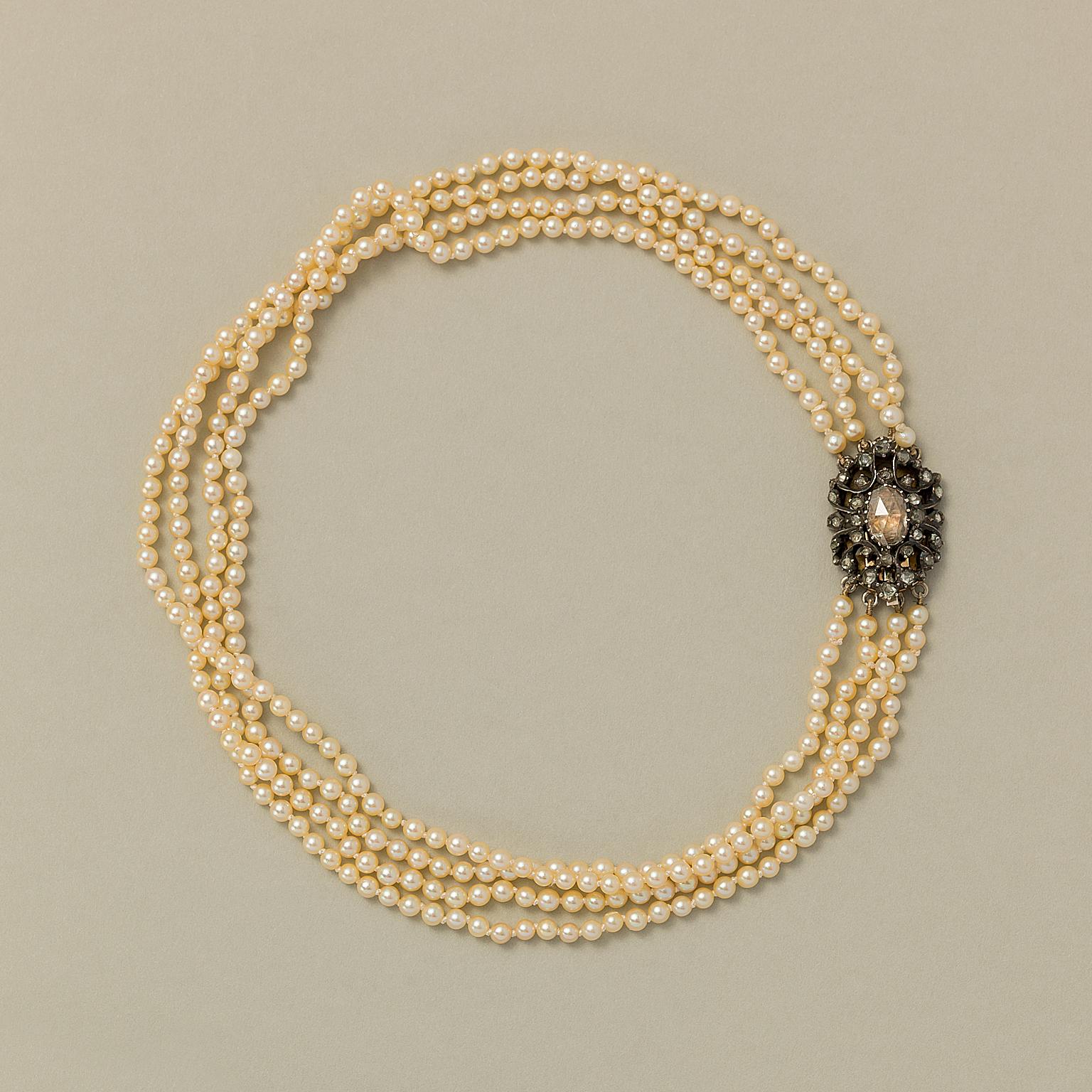 A four-row cultured pearl necklace with a 14 carat gold clasp that is made out of an antique silver and rose cut element, set with one oval rose-cut diamond (app. 9.7x 6.5 mm) and 36 small rose-cut diamonds. 

weight: 31.47 grams
length: 37.5 cm
