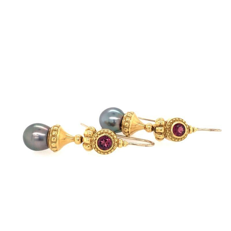 One pair of black Tahitian pearl and garnet 18K yellow gold dangling earring featuring two pearls each measuring 10 millimeters in diameter and two bezel set, round brilliant cut garnets totaling 1.50 ct. Circa 1960s.

Ornate, distinctive,