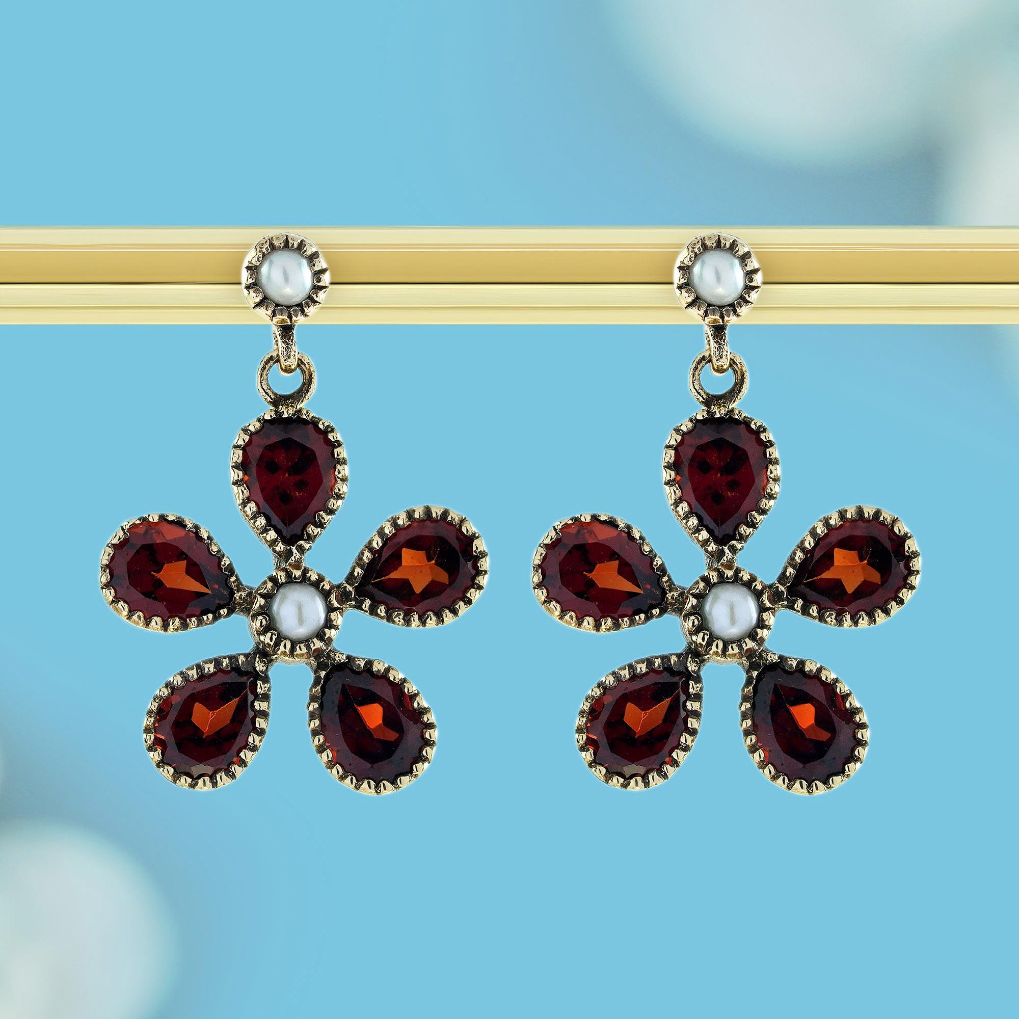 Gönnen Sie sich die Schönheit klassischer Eleganz mit diesen floralen Ohrringen aus Naturperlen und Granat im Vintage-Stil. Das Herzstück eines jeden Ohrrings ist eine schimmernde Naturperle, die Raffinesse und Anmut ausstrahlt. Rundherum sind